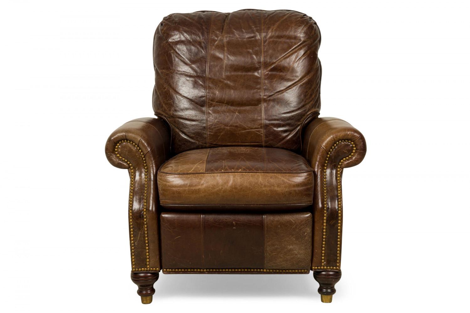 Poltrona / poltroncina reclinabile contemporanea rivestita in pelle marrone con cuscino di seduta e di schienale attaccato, con chiodi decorativi in ottone e poggiapiedi estensibile, che poggia su due piedi anteriori in legno tornito e due piedi