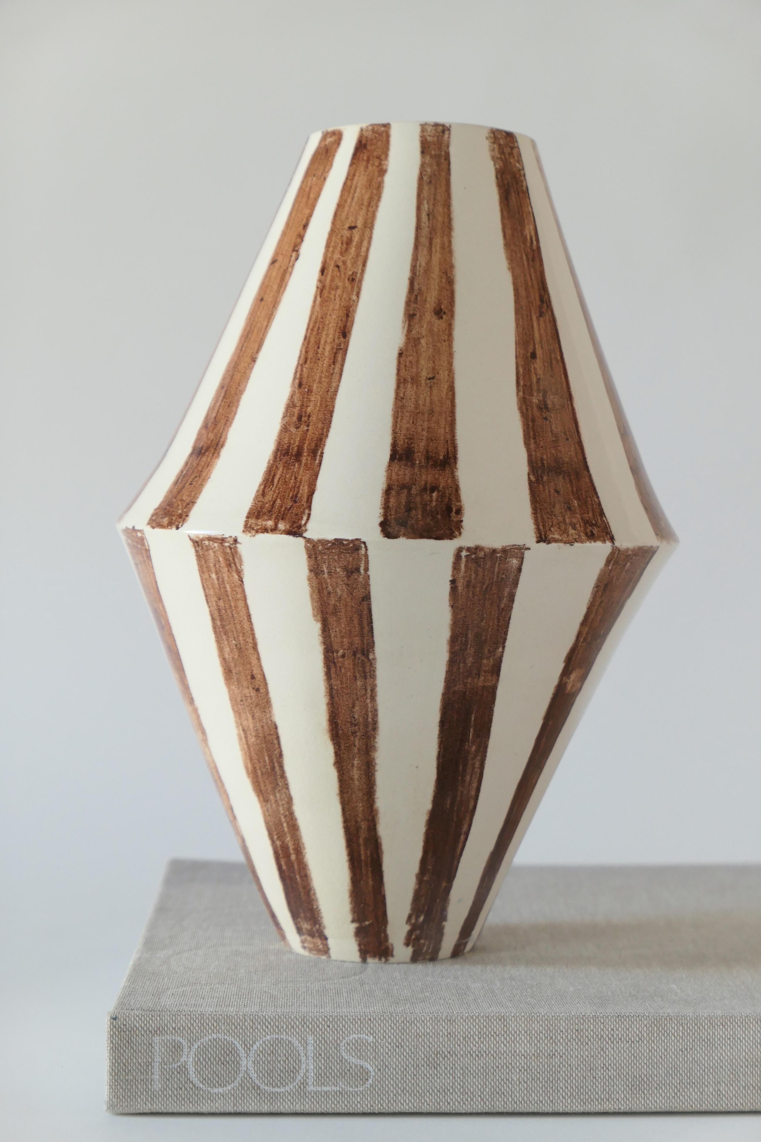 Off-white hand-built stoneware vase hand-painted with brown crayon stripes and finished with a thin clear glaze. 

Karina Vieira is a Brooklyn-based ceramicist focusing on handmade vessels. 

Her work references various styles, touching on the