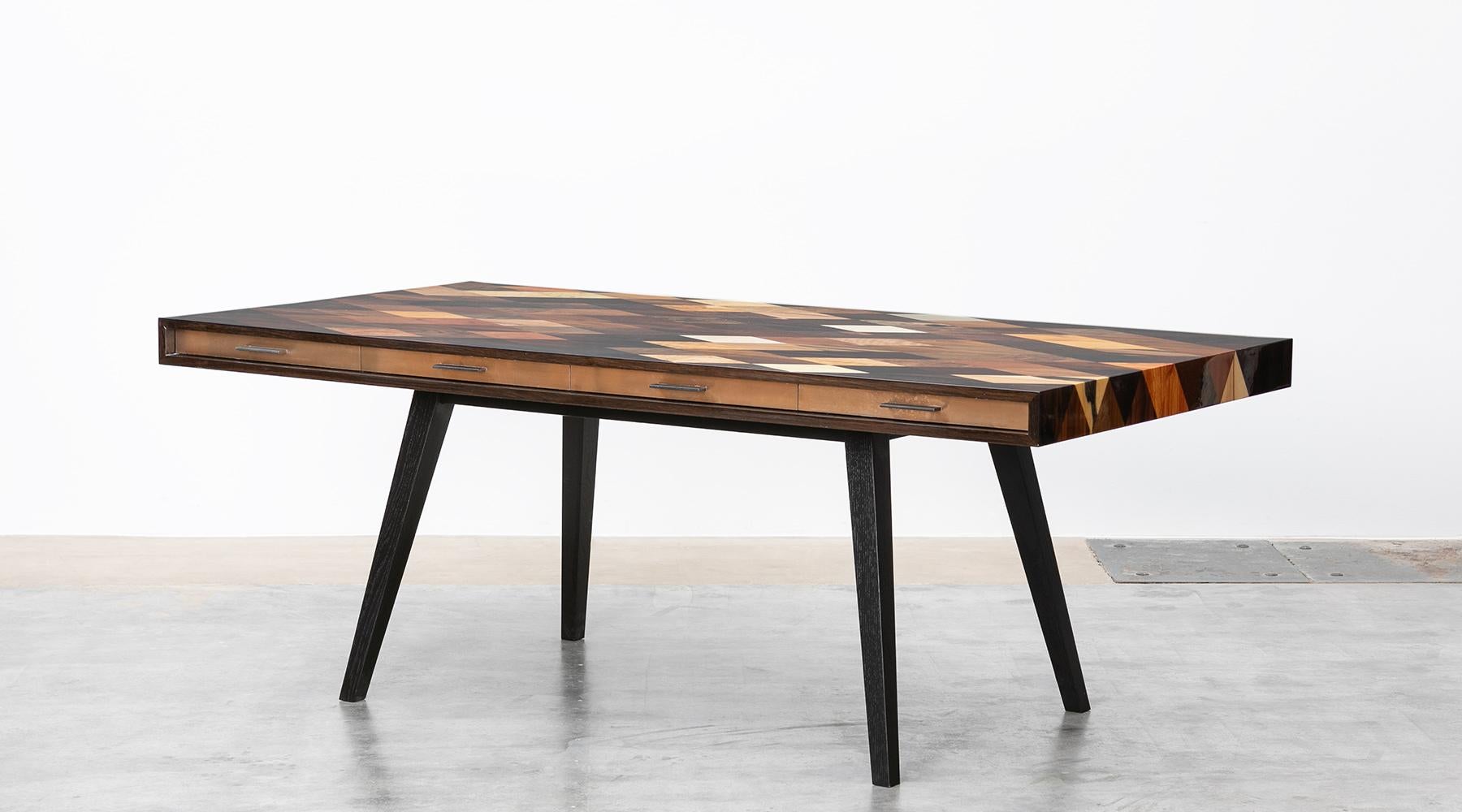 Stunning desk by contemporary German Artist Johannes Hock. A well proportioned body situated on a solid wood base. The surface of rhombs, joined in different veneers, apparently flowing over the table edges. Bronze drawers with ebony handles