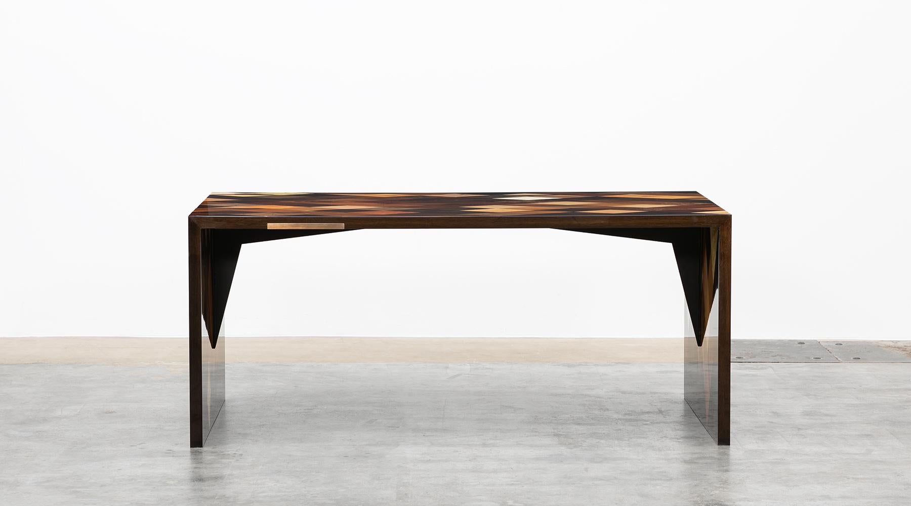 Desk by contemporary German artist Johannes Hock.
Its archetypical and reduced form in interaction with the marquetry of the shell unfolds the special attraction of the piece.
The table is made of diamond shaped veneers of various origin such as