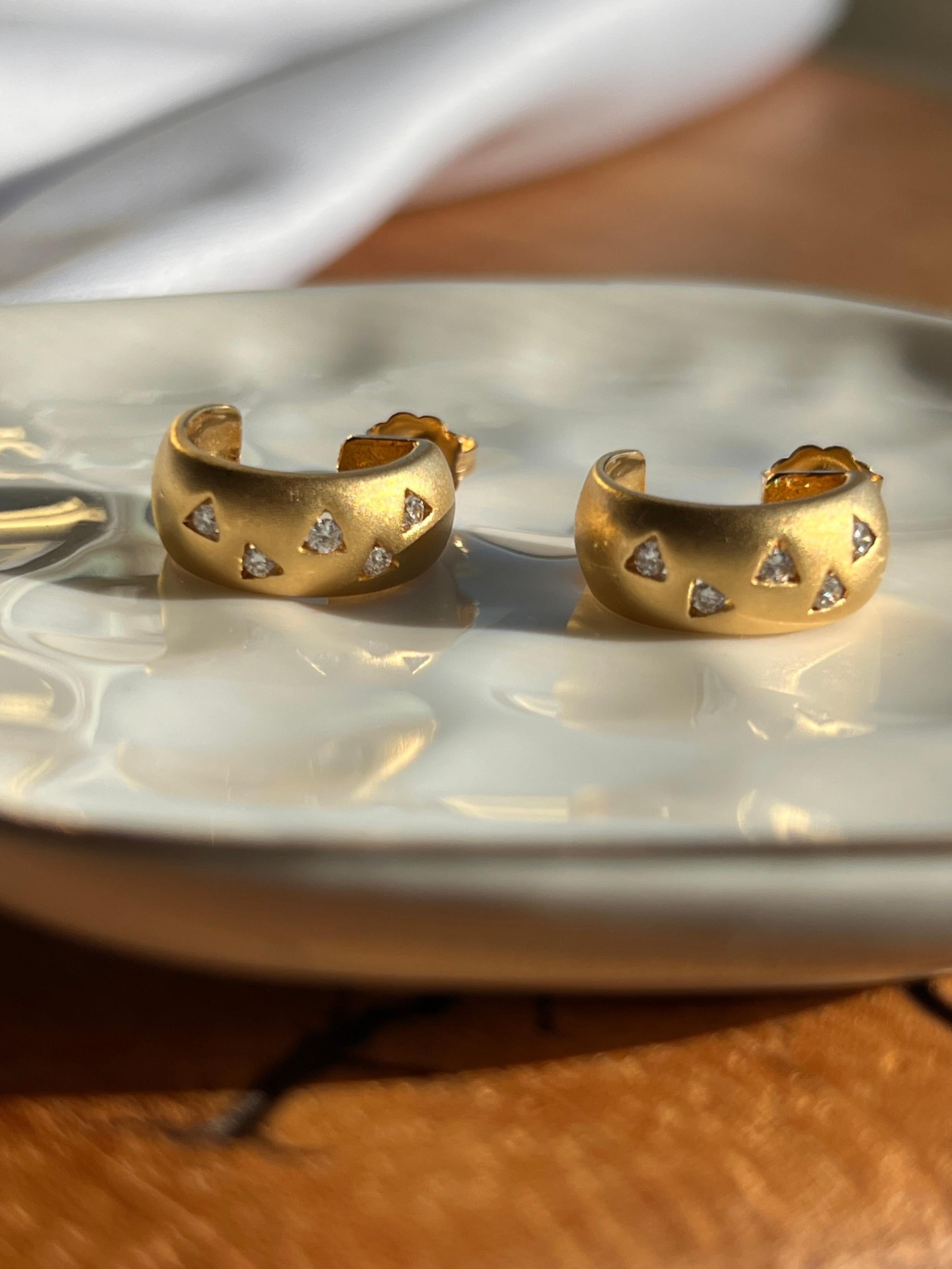 Un paio di orecchini a mezzo cerchio spazzolati in oro giallo 18 carati, ciascuno con 5 diamanti tondi brillanti, per un totale di circa 0,18 carati tra i due, con colore G-H e purezza I1-I3. Realizzati con una morbida finitura satinata che ne