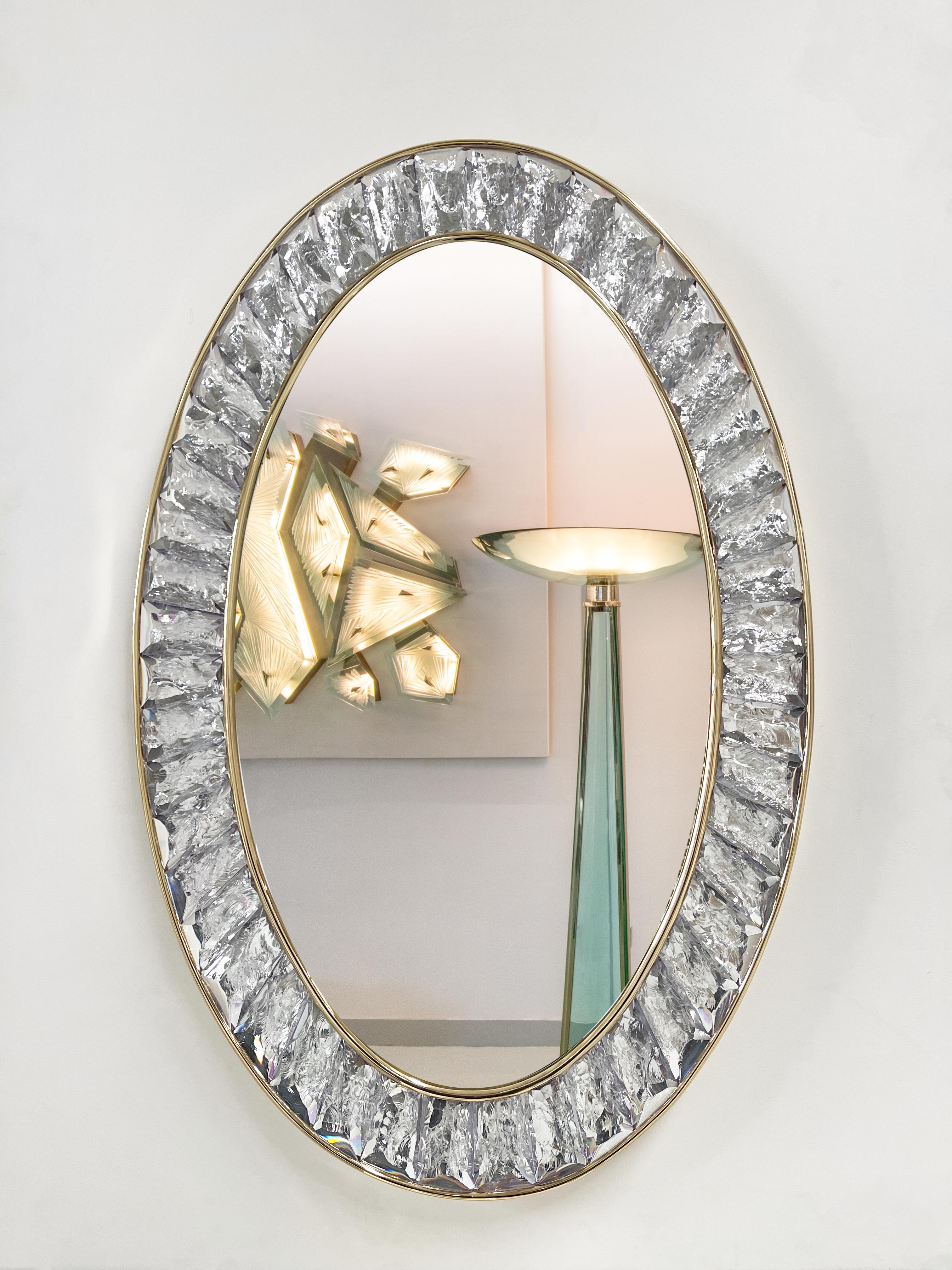 2022 Contemporary by Ghirò Studio Wall Mirror. Martelè wall mirror is an artistic object of pure art and italian design. The support structure is in 24 kt polished gold plated brass. The oval frame of the mirror is made up of hand-carved crystal