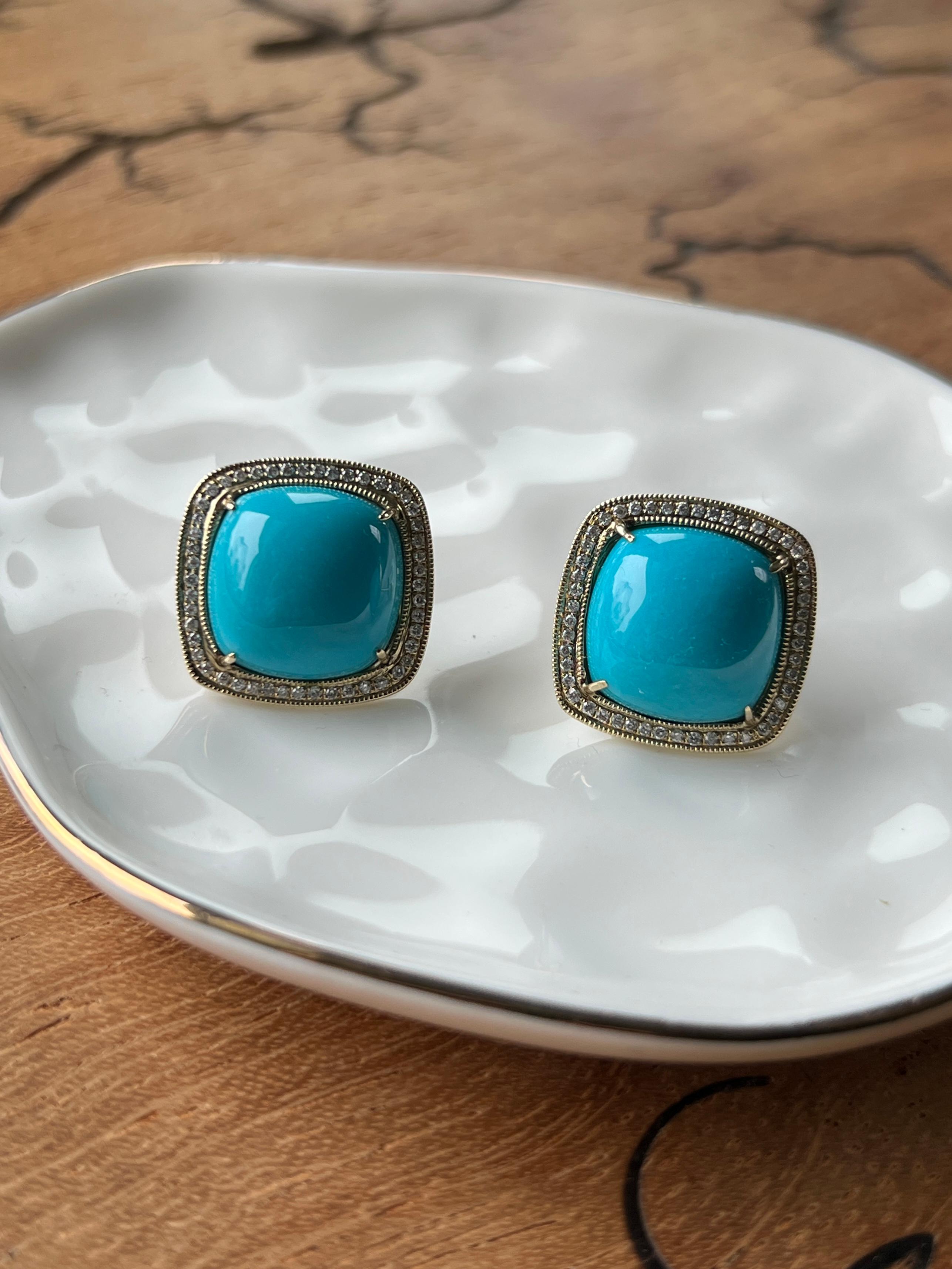 Une paire de boucles d'oreilles contemporaines de style halo en or jaune 14 carats, chacune centrée sur une turquoise cabochon en forme de coussin mesurant 14 x 14 mm. Les turquoises sont encadrées par un halo scintillant de diamants ronds et