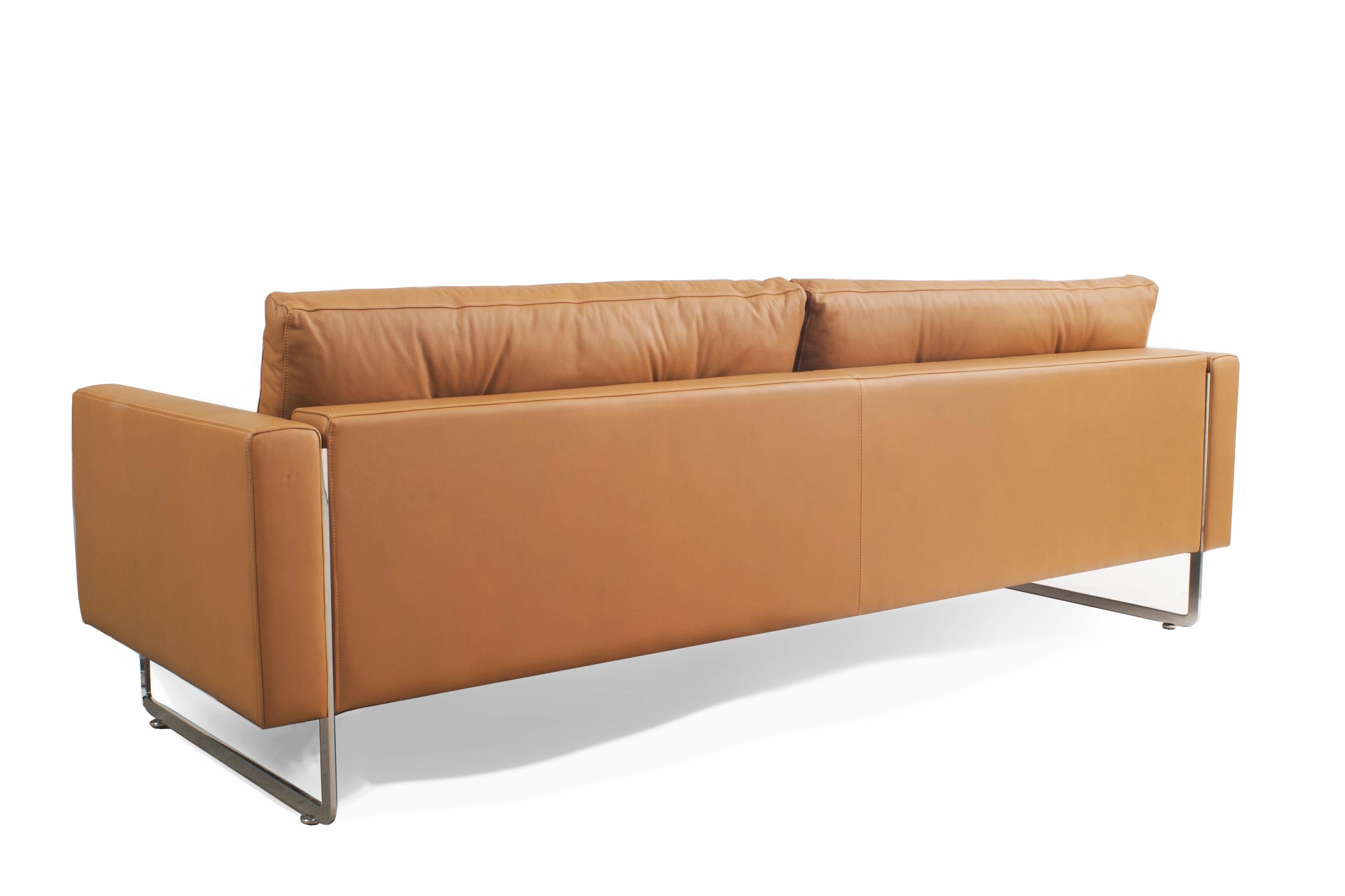 Contemporary caramel brown leather 3-seater sofa with two button-tufted back cushions, square arms, and chrome metal legs.