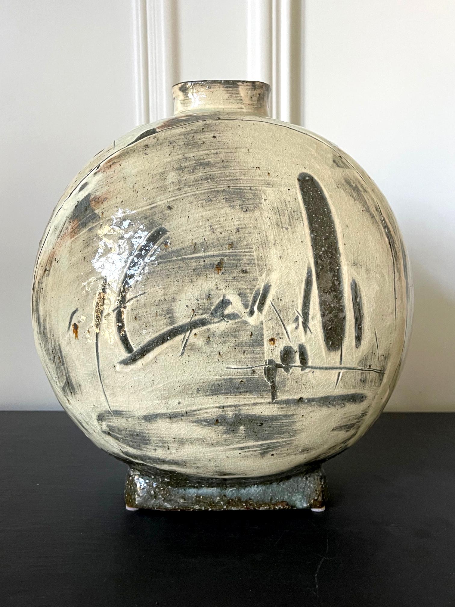 A contemporary ceramic stone ware vessel in the form of a flat moon flask by Korean artist Kang Hyo Lee (South Korean, b. 1961). The work is inspired by traditional Korean Buncheong ware. It is a new interpretation of the white slip glaze with
