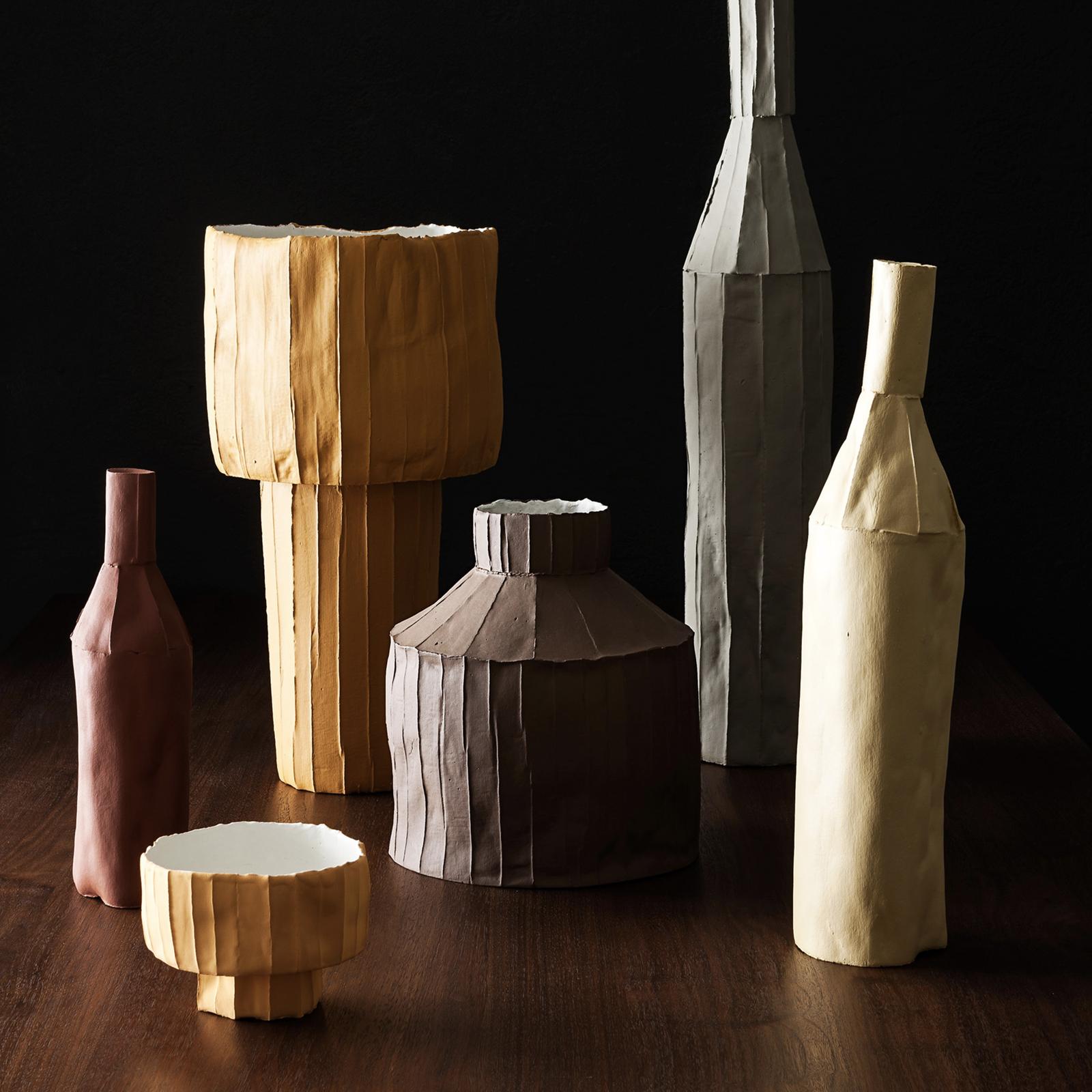The evocative and distinctive texture of this sculpture is a trademark of Italian ceramist Paola Paronetto, whose creativity gives life to original objects inspired by the real world. This bottle-shaped piece is handcrafted of paper clay, a mixture
