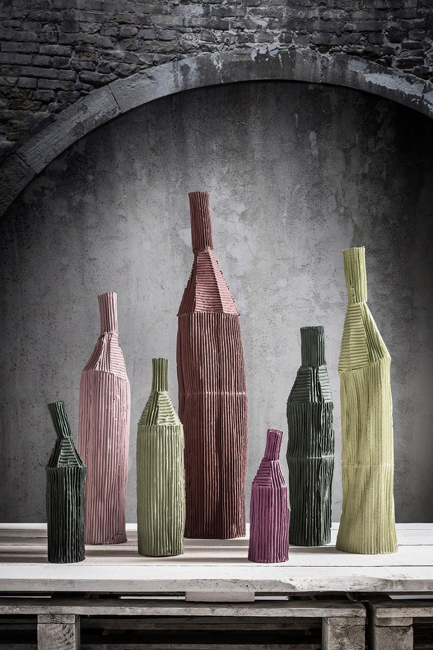 Diese elegante Flasche zeichnet sich durch vertikale und horizontale Rillen aus, die in Kombination mit der hohen, zylindrischen Form ein Gefühl der Ausgewogenheit vermitteln, das jedem Dekor einen einzigartigen Reiz verleiht. Dieses Deko-Objekt aus