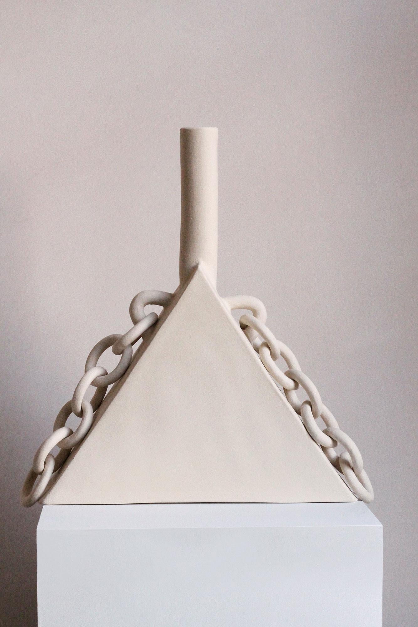 Handmade from stoneware, this abstract sculpture features ceramic chains that hang from the triangular body of the sculpture, adorning the form like jewellery. Created by Miyelle at her studio in Hackney, London, this unique piece is part of her