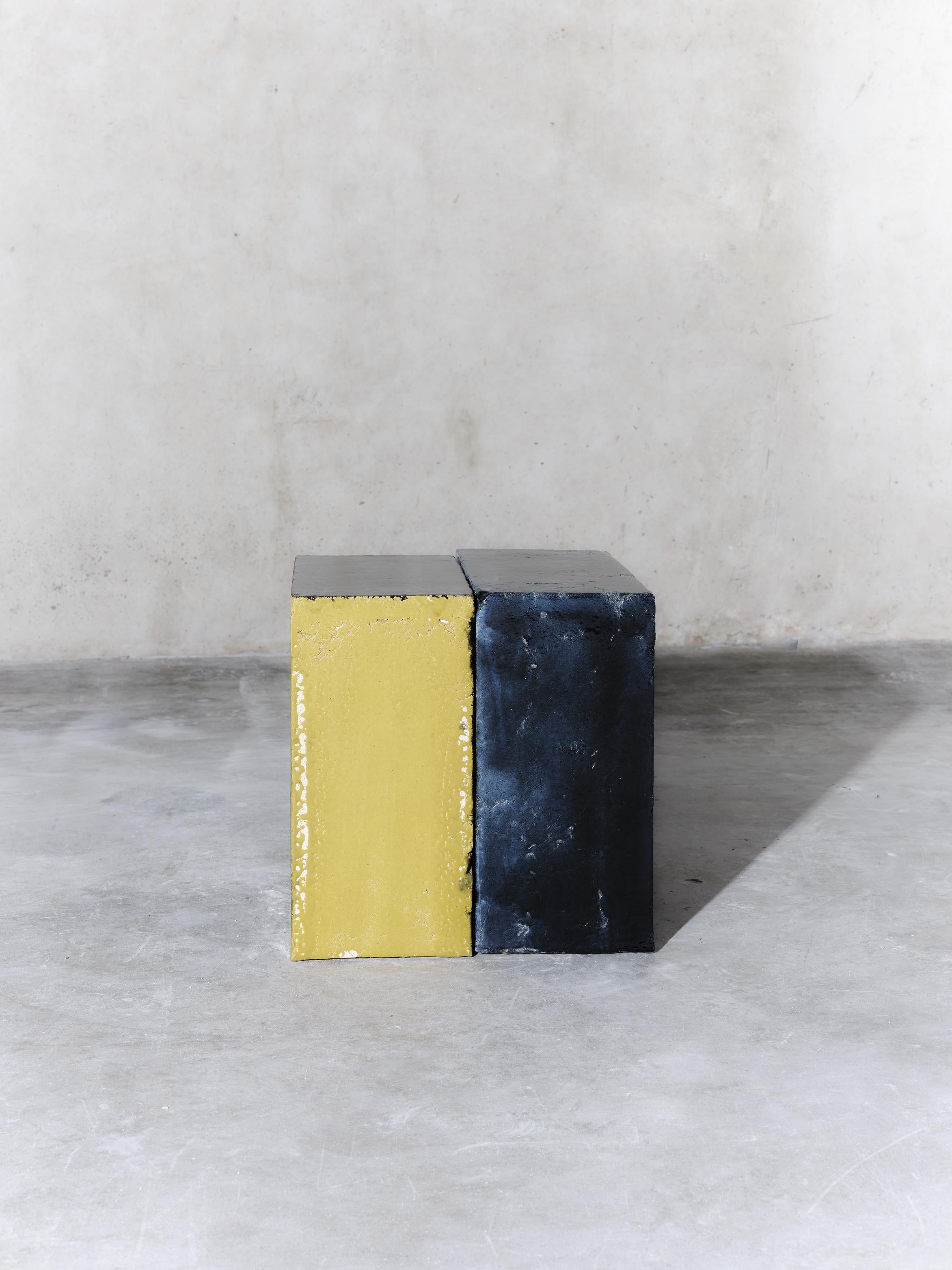 Mesa auxiliar de barro azul y amarillo fabricada a mano en el taller de Apparatu de Barcelona. Los diferentes cuerpos de arcilla se mezclan con fibras naturales como maíz, paja o paja de brezo. Las piezas se funden a mano, creando una estructura de