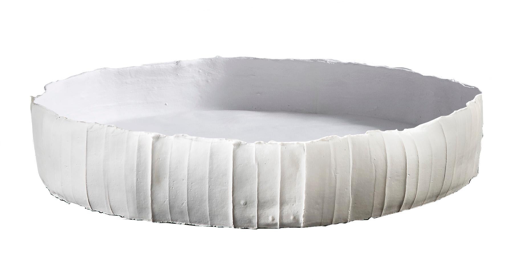 This one-of-a-kind tray in white paper clay (clay enriched with cellulose and natural fibers) will infuse contemporary glamour and sculptural flair in any dècor. Sophisticated in its simplicity, this white tray features an irregular circular shape