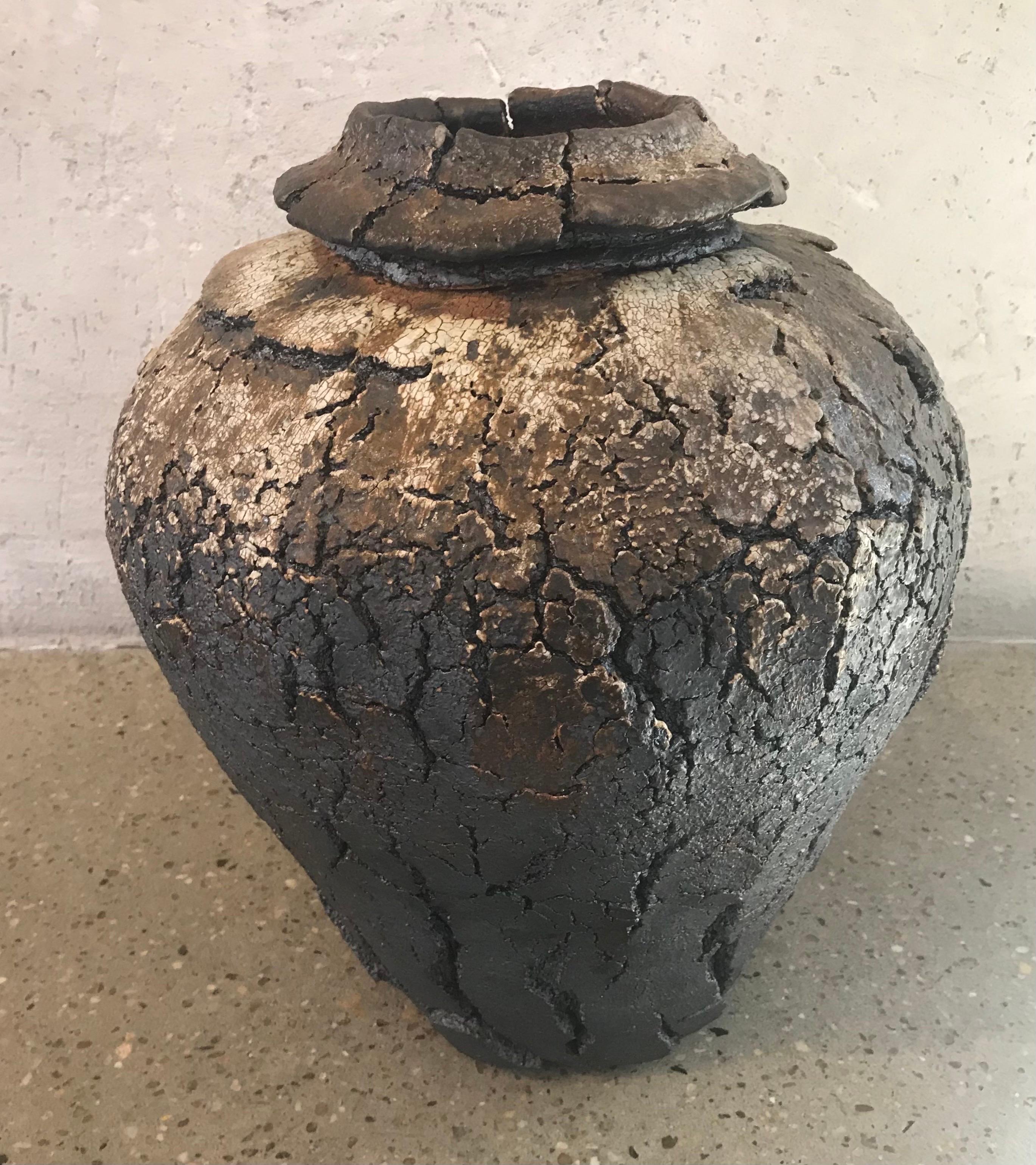 This over-fired clay vessel was hand made by ceramicist Jay Stroman. The rustic crackled look is juxtaposed but the interior of the piece which shows a glass bottom appearing to be puddle of still water resting at the bottom of the piece.