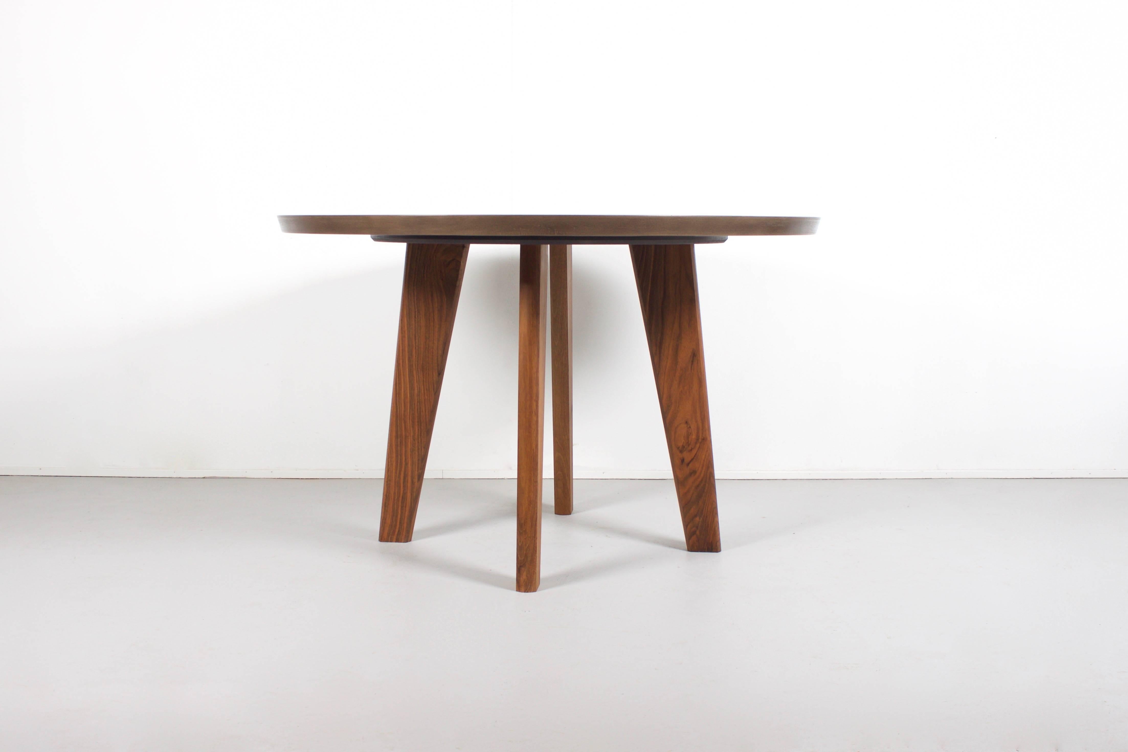 Beautiful contemporary round dining table.

This table is equipped with feet in solid walnut which have been oiled. 

The top is made from a polished ceramic with a brown marble look.

This top has many advantages: it is scratchproof, stain
