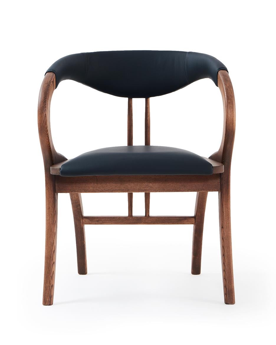 The chair features extraordinary design with curved back legs that form part of the armrests and back support.
Handcrafted of solid wood frame in walnut color and upholstered in black faux leather.
We offer multiple customization options. COM and