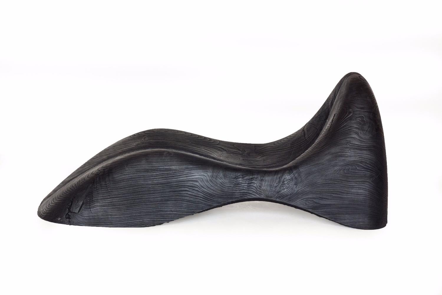 Chaise lounge made from aromatic cedar, composed of two symmetrical parts that are aligned and separated by a central fissure. The design is sculptured in the shape of a human body that is enveloped from head to foot. The products are made from