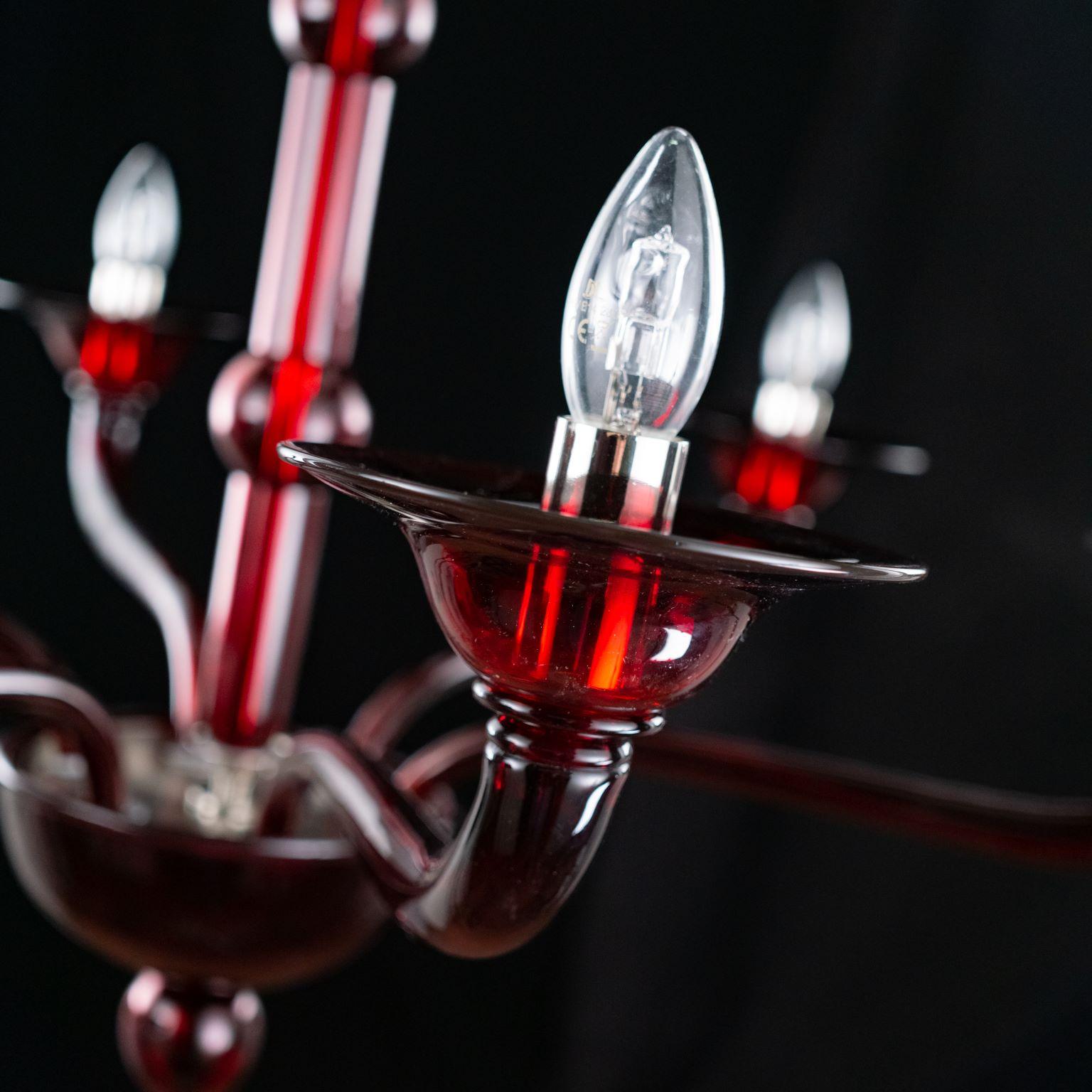 Multiforme Tobia chandelier 6 lights. red Murano glass with castle arms climbing arms.
The blown glass chandelier Tobia harks back to the design typical of the first half of the 20th century.
This lighting work is characterized by a tube-shaped