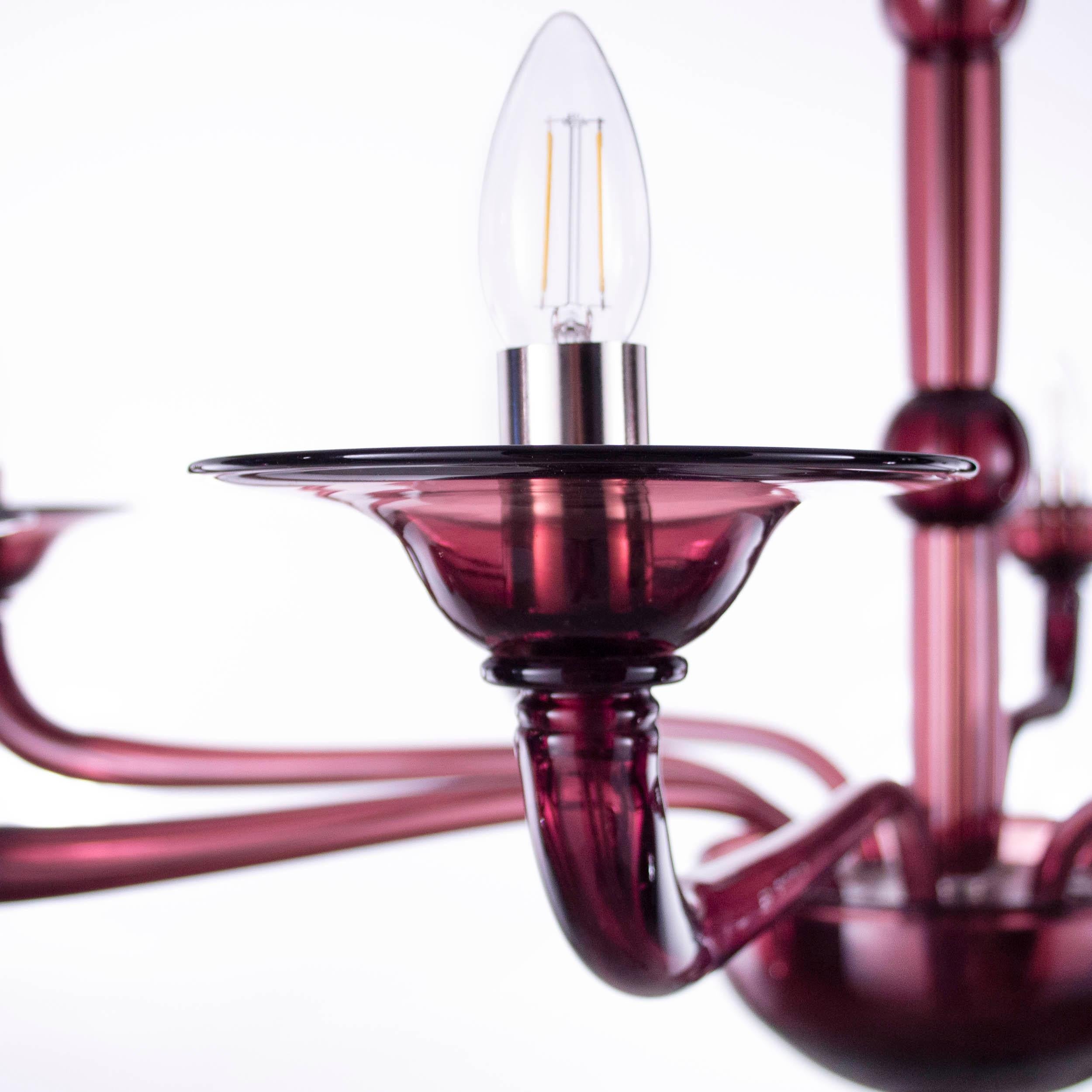 Multiforme Tobia chandelier 8 lights. Aubergine Murano glass with castle arms climbing arms.
The blown glass chandelier Tobia harks back to the design typical of the first half of the 20th century.
This lighting work is characterized by a