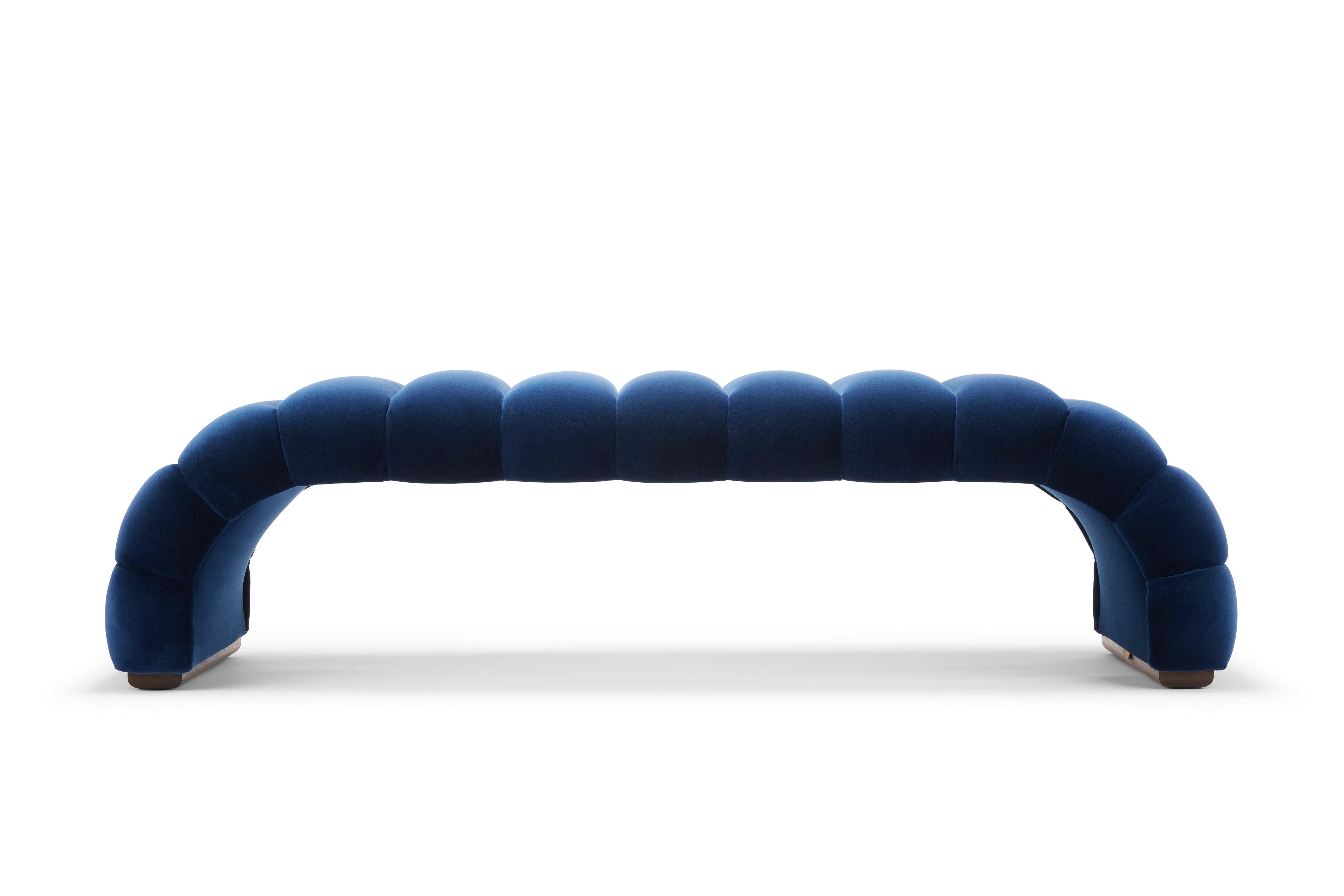 Die Fleure-Bank mit ihren tadellosen geriffelten Details ergänzt eines unserer charakteristischen Stücke, das Fleure-Sofa. Hier abgebildet mit Designer Guild Denim blauem Baumwollsamt gepolstert. Die Füße sind aus naturgeöltem Nussbaumholz