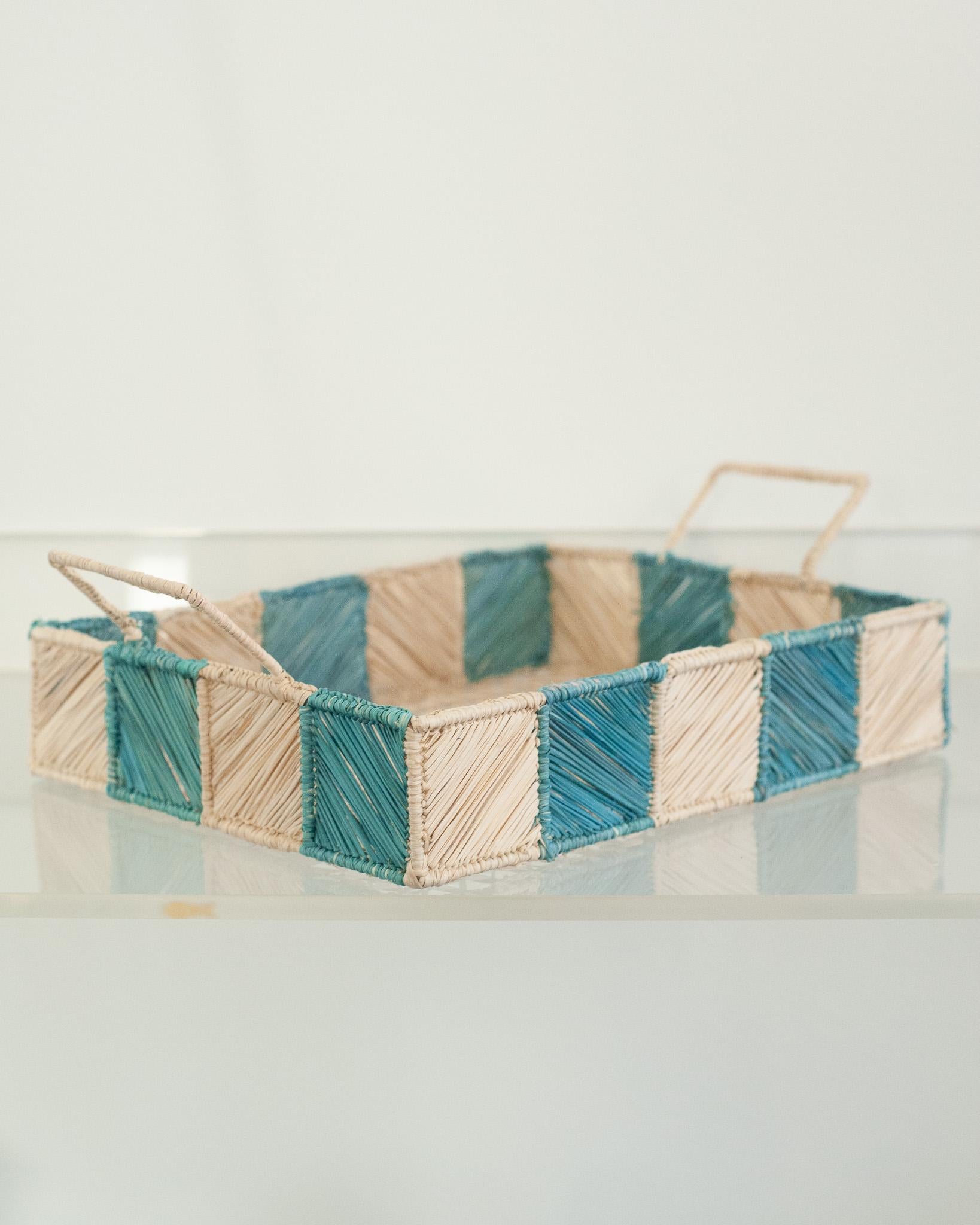 Uplift your table with this stunning handwoven rattan tray with sky blue and natural checkered sides and handles. Finely crafted by expert artisans, this piece showcases the classical technique of weaving in a modern way. From Jean Michel Frank to