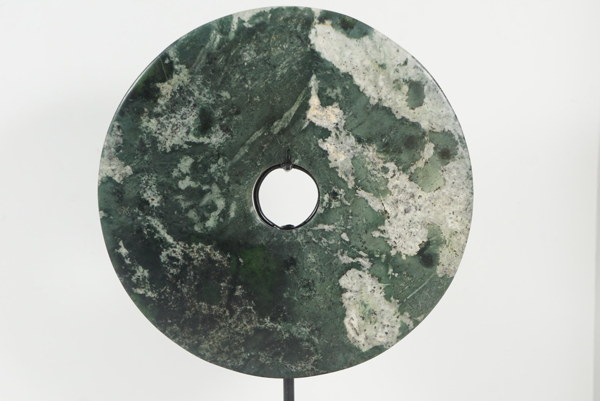 This large finely veined jade bi disc is of a dream stone quality. Of contemporary creation, the bi disc is mounted on a stand but is removable for inspection. The Bi Disc is an ancient symbol of ritual origin in China. Circular in form these