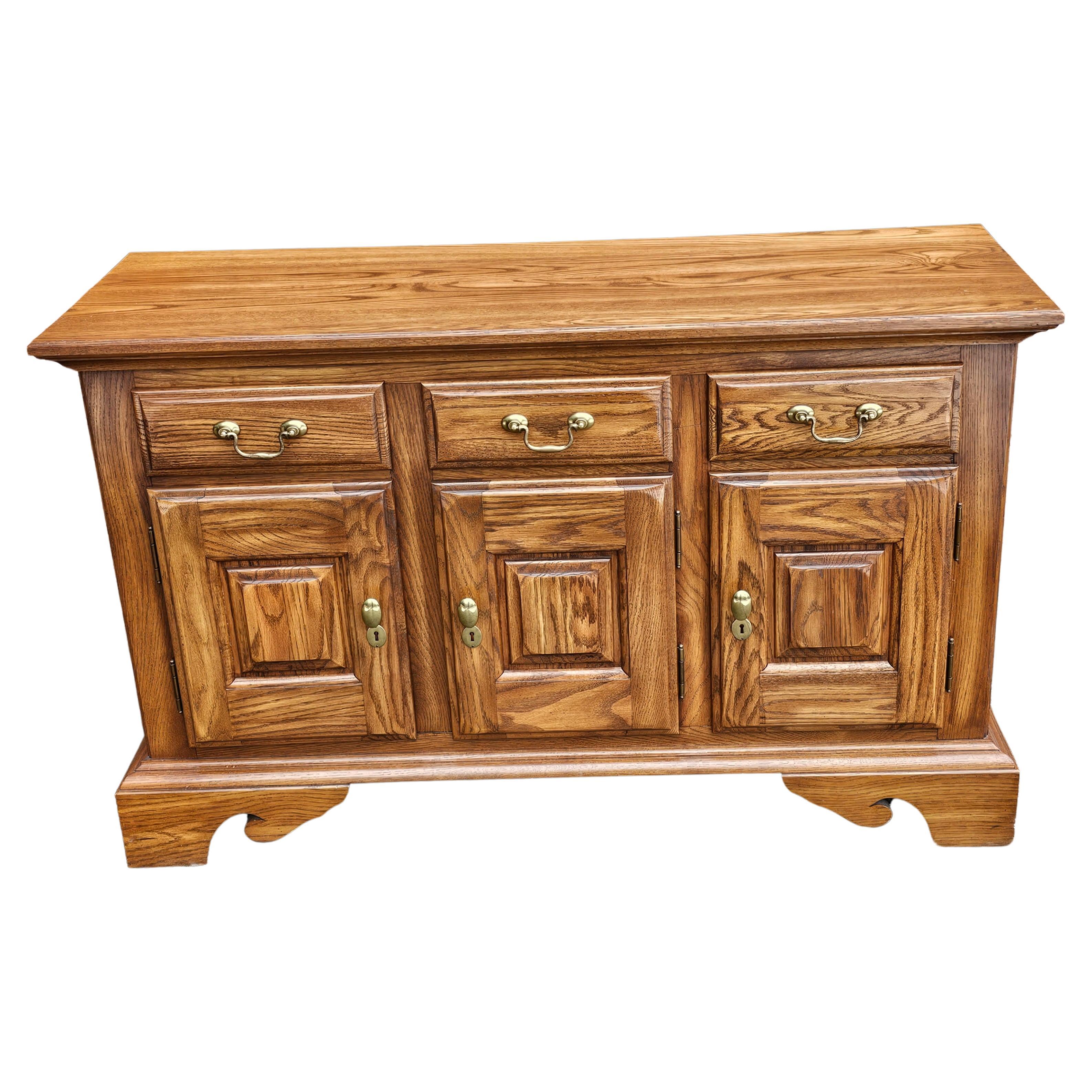 A Pennsylvania House Contemporary Chippendale Style solid oak sideboard Buffet featuring rare 3 drawer and compartmented two door bottom storage cabinet with removable shelf and single door cabinet. Very good vintage condition. Measures 52