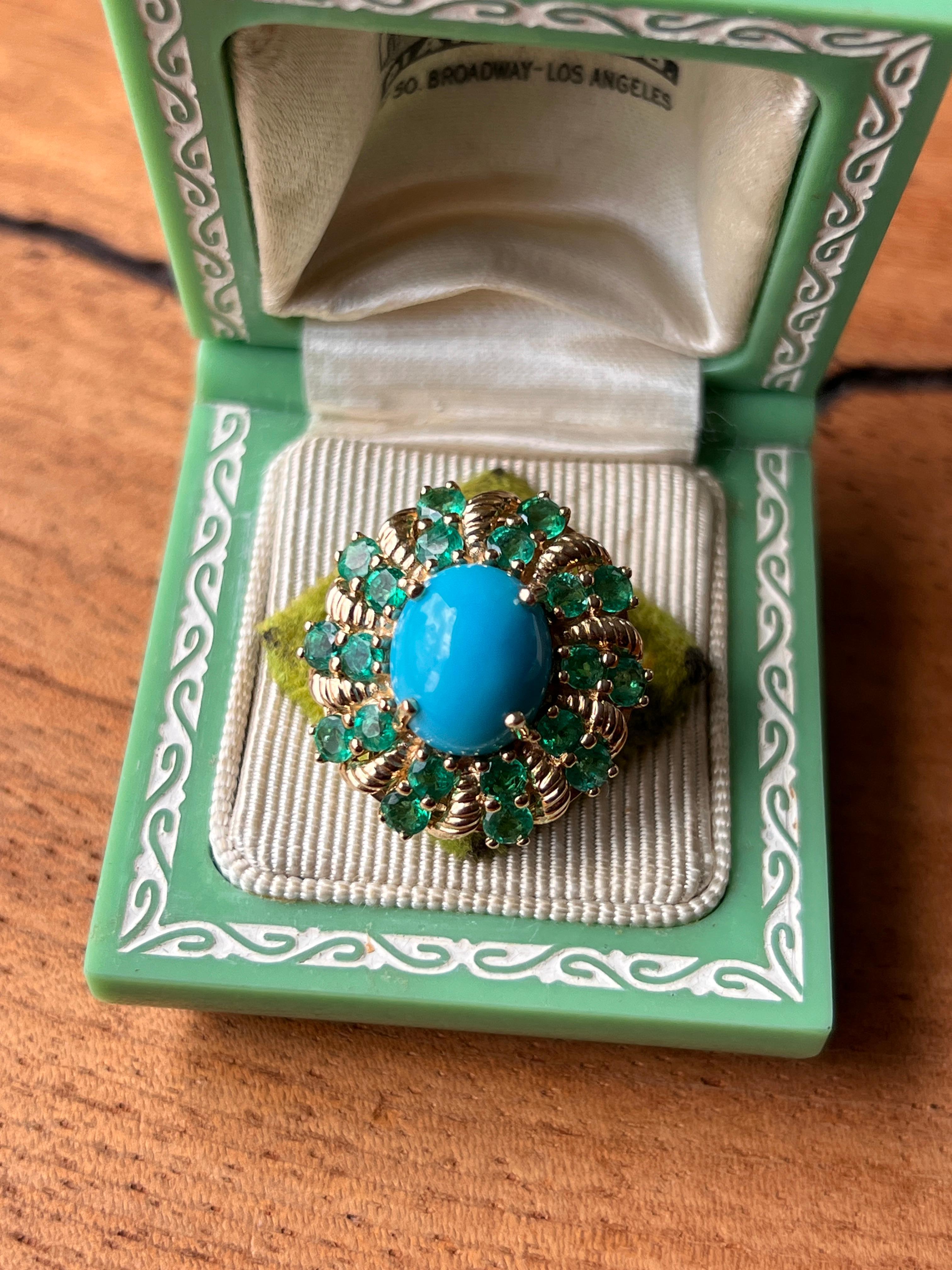 One striking 14 karat yellow gold cocktail ring featuring a vivid oval 
cabochon chrysocolla-in-chalcedony, often referred to as blue chalcedony, measuring approximately 12 x 10mm. The bold centerpiece is surrounded by a halo of twenty round