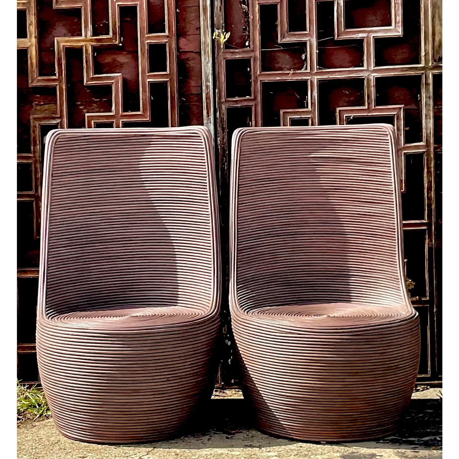 A gorgeous pair of Contemporary Coastal lounge chairs. Made from a chic coiled pencil reed in a warm chocolate brown finish. High blade back and wide seat. Acquired rom a Palm Beach estate.