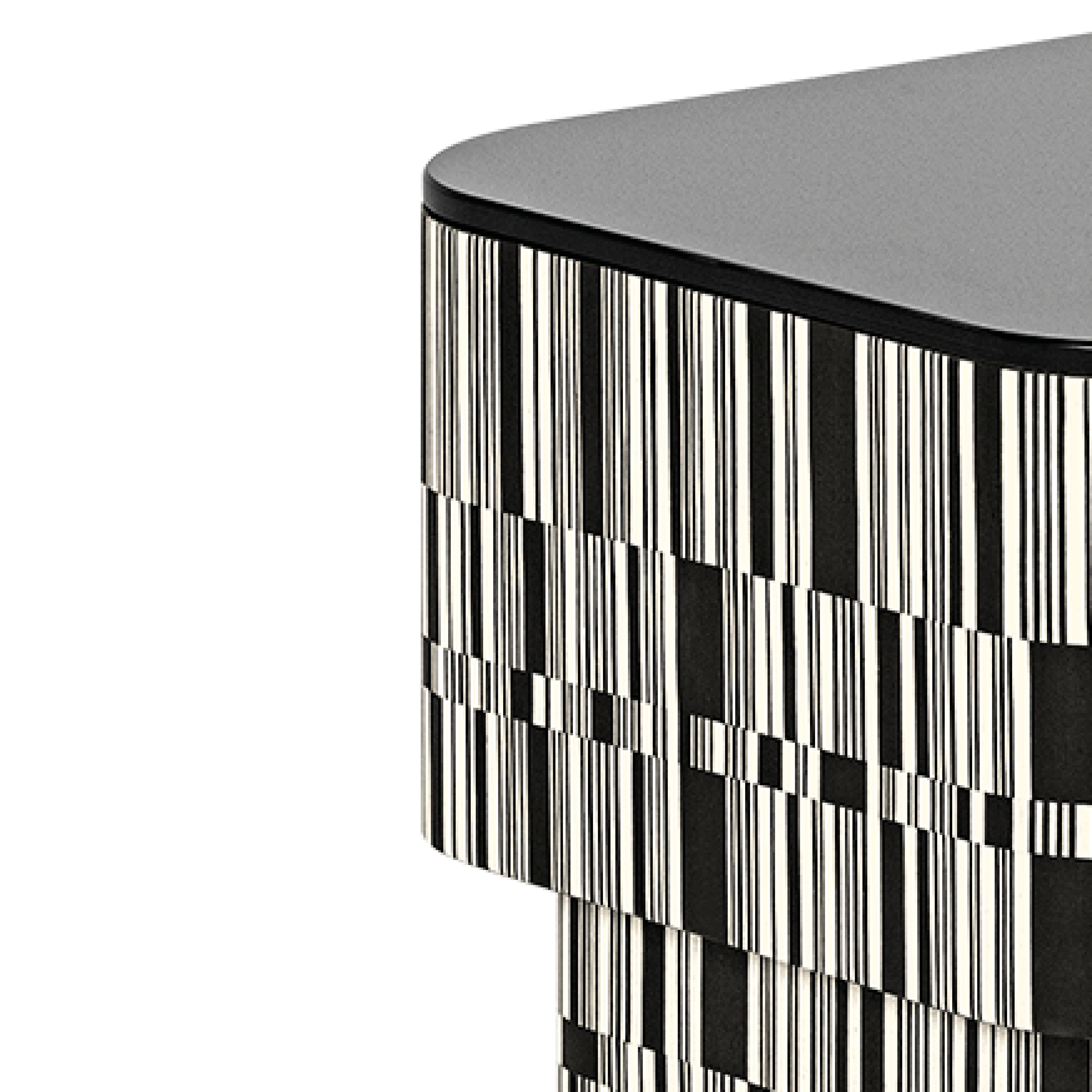 La structure de la table d'appoint Enigma est revêtue de bois, traité avec une incrustation en fil croisé avec des nuances blanches et noires qui s'alternent de manière irrégulière. Il présente une finition Matrix mate et un plateau en verre noir.