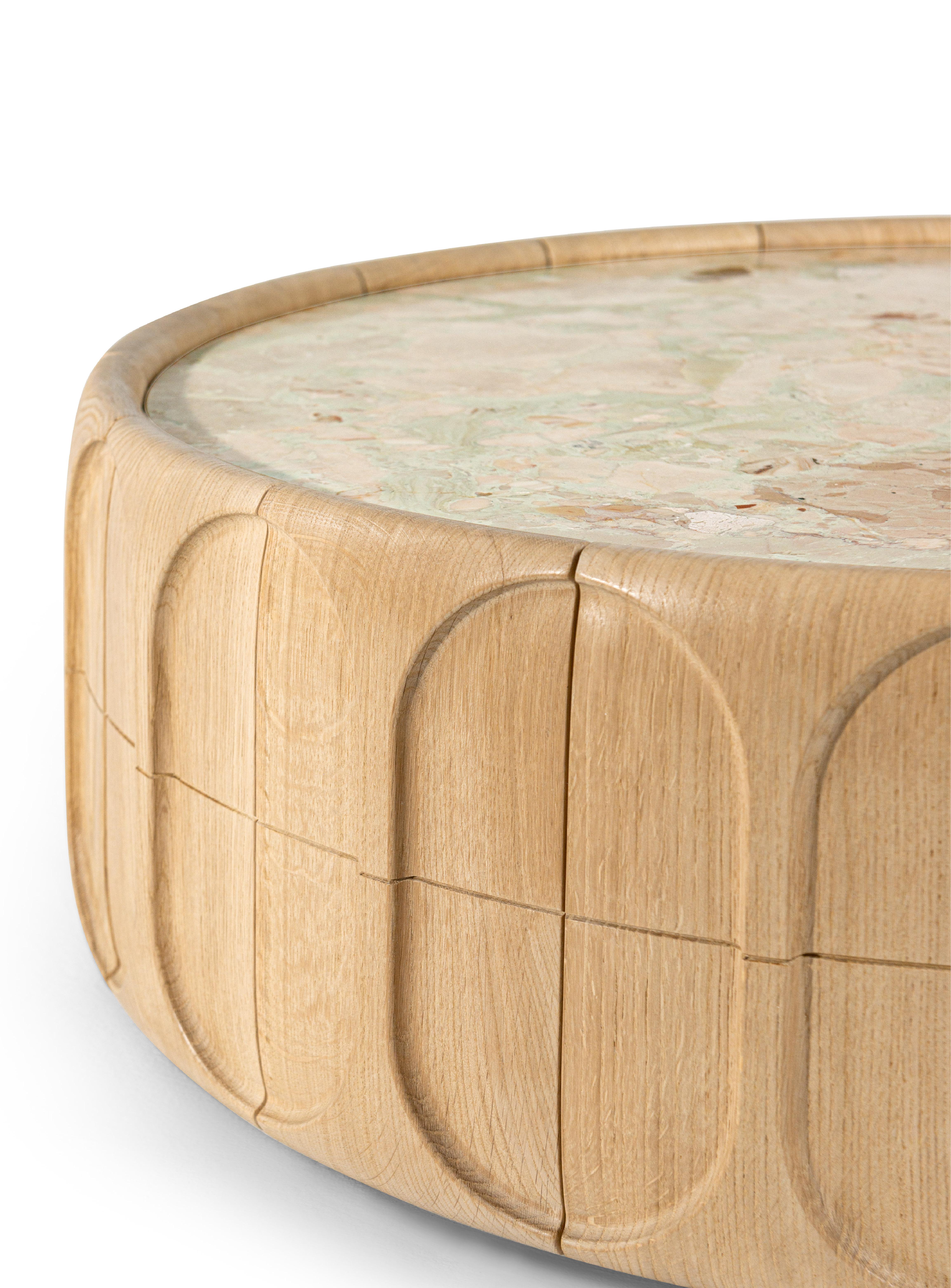 Der konkave Couchtisch hat ein minimalistisches, aber raffiniertes Design, das durch die Struktur aus natürlichem Eichenholz und die Platte aus strukturiertem Ceppo Romano-Marmor betont wird. Er bereichert den Wohnbereich mit einer skulpturalen Note