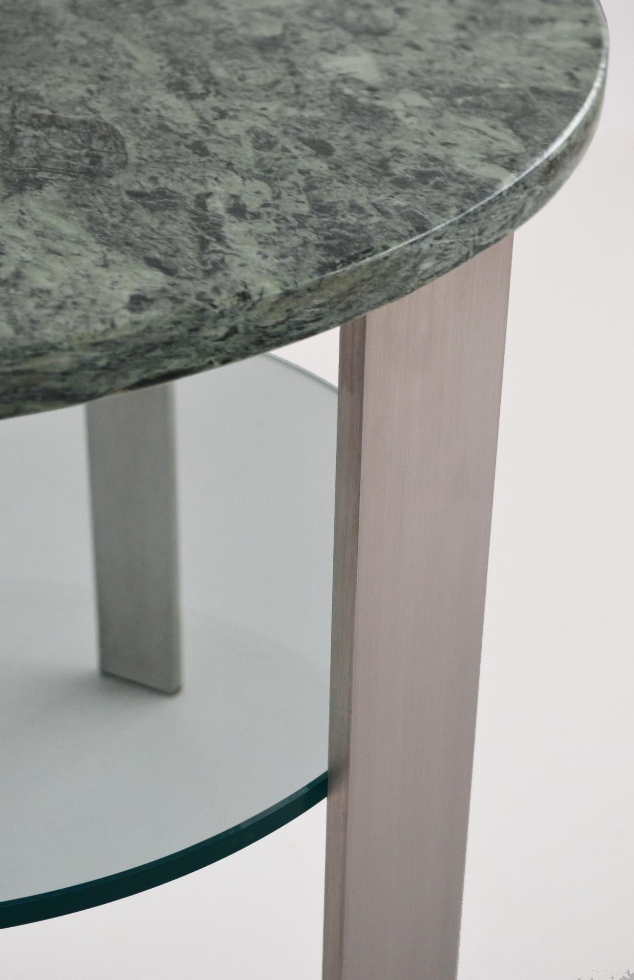 Ce splendide tavolino dans le style moderne du milieu du siècle dernier a été réalisé à la main en utilisant trois types de matériaux : acciaio inossidabile satiné pour les trois poutres et le piano supérieur, marbre italien Verde Issoire et vetro