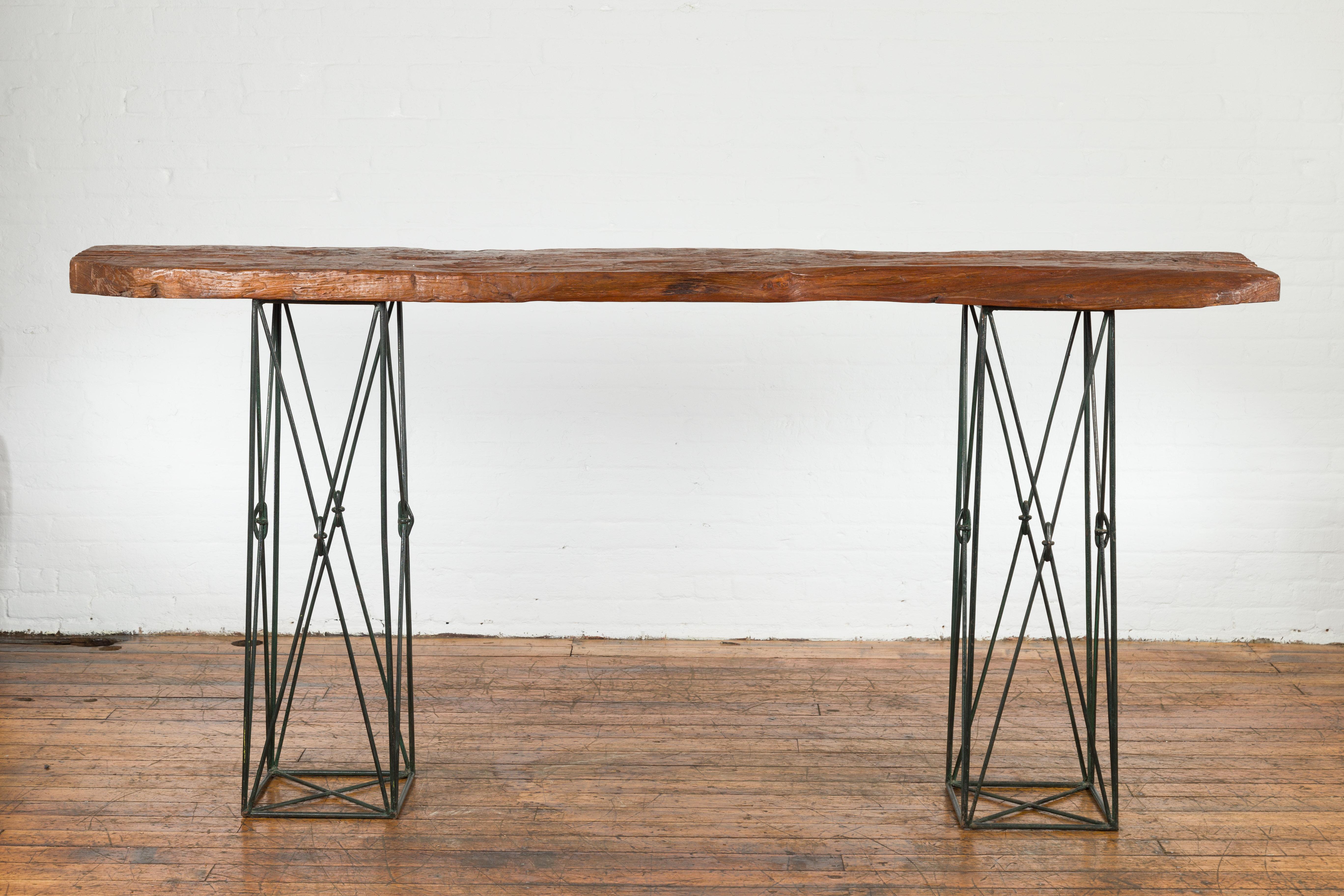 A unique contemporary console table made with a Javanese reclaimed wood top and two metal suspension bases from Thailand, with discreet dark green painted hue. Capturing our attention with its airy presence and perfect mix of old and new, this