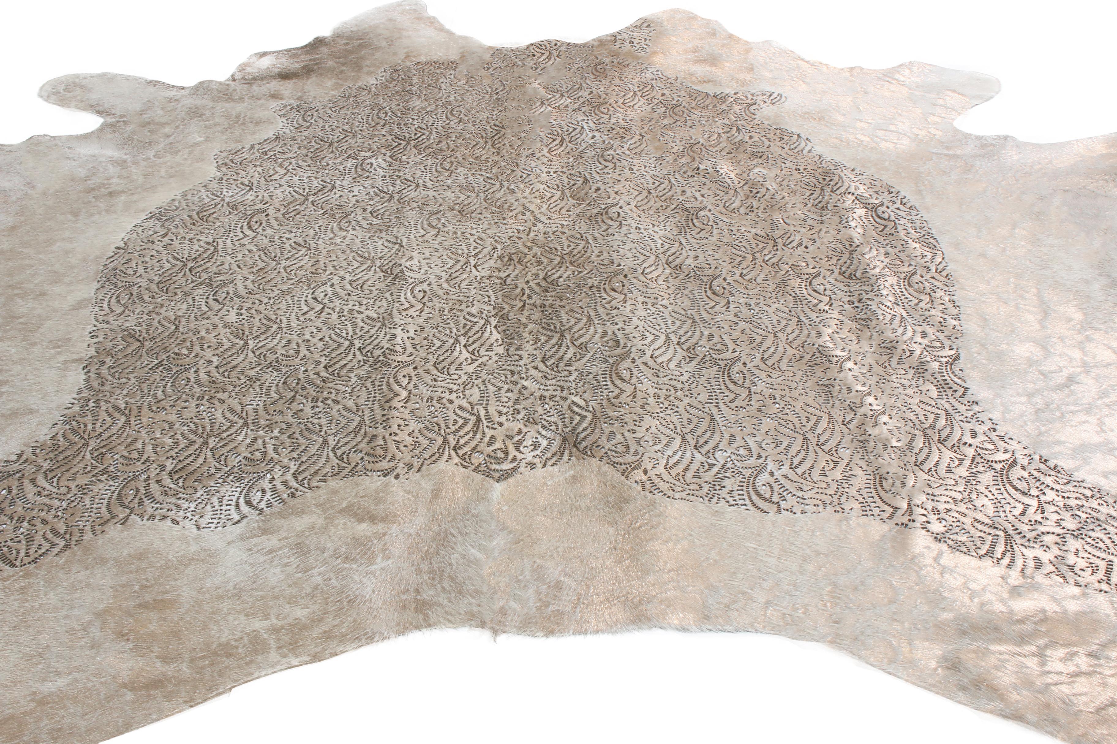 Originating from the United States, this contemporary leather cowhide rug has natural white colourways with minimal gray, metallic accents to its hide; a distinct stylistic addition for more modern, luxurious spaces. This tannery maintained the