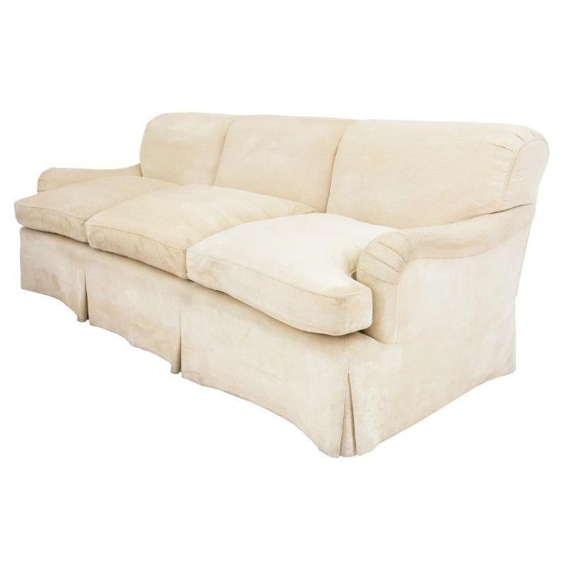 A cream contemporary styled chenille, three seat sofa with loose seat cushions, low profile scroll arms, a three-part back and tailored skirt with pleats to mirror the seat breaks.  Constructed of 50/50 poly and down fill.  Some stains consistent