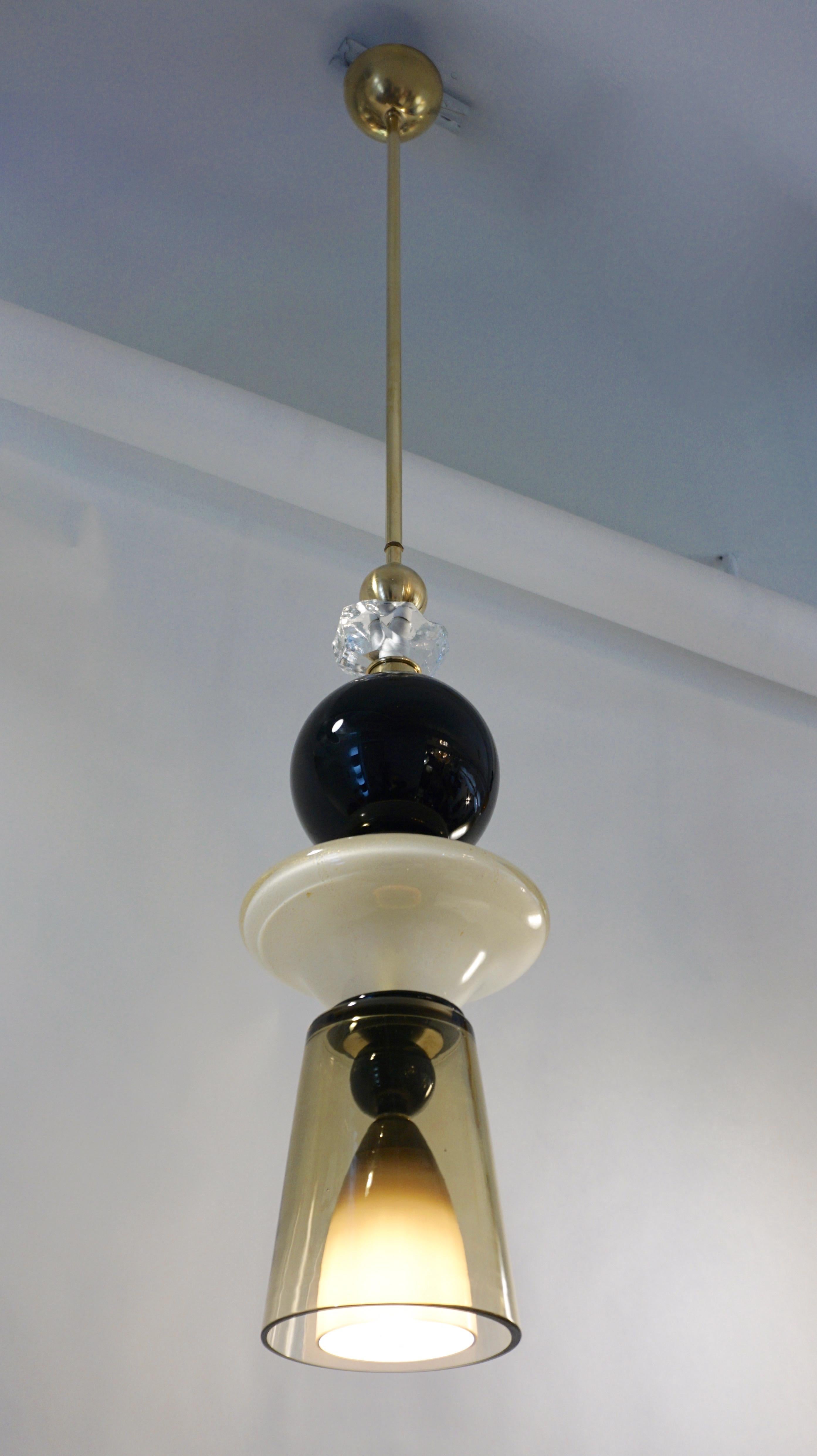 Fun and elegant Italian pendant chandelier, entirely handcrafted, of organic modern design consisting of a succession of elements: black opaline glass and brass spheres, a hand-cut jewel like rock glass decoration, a saucer shaped ivory white mouth