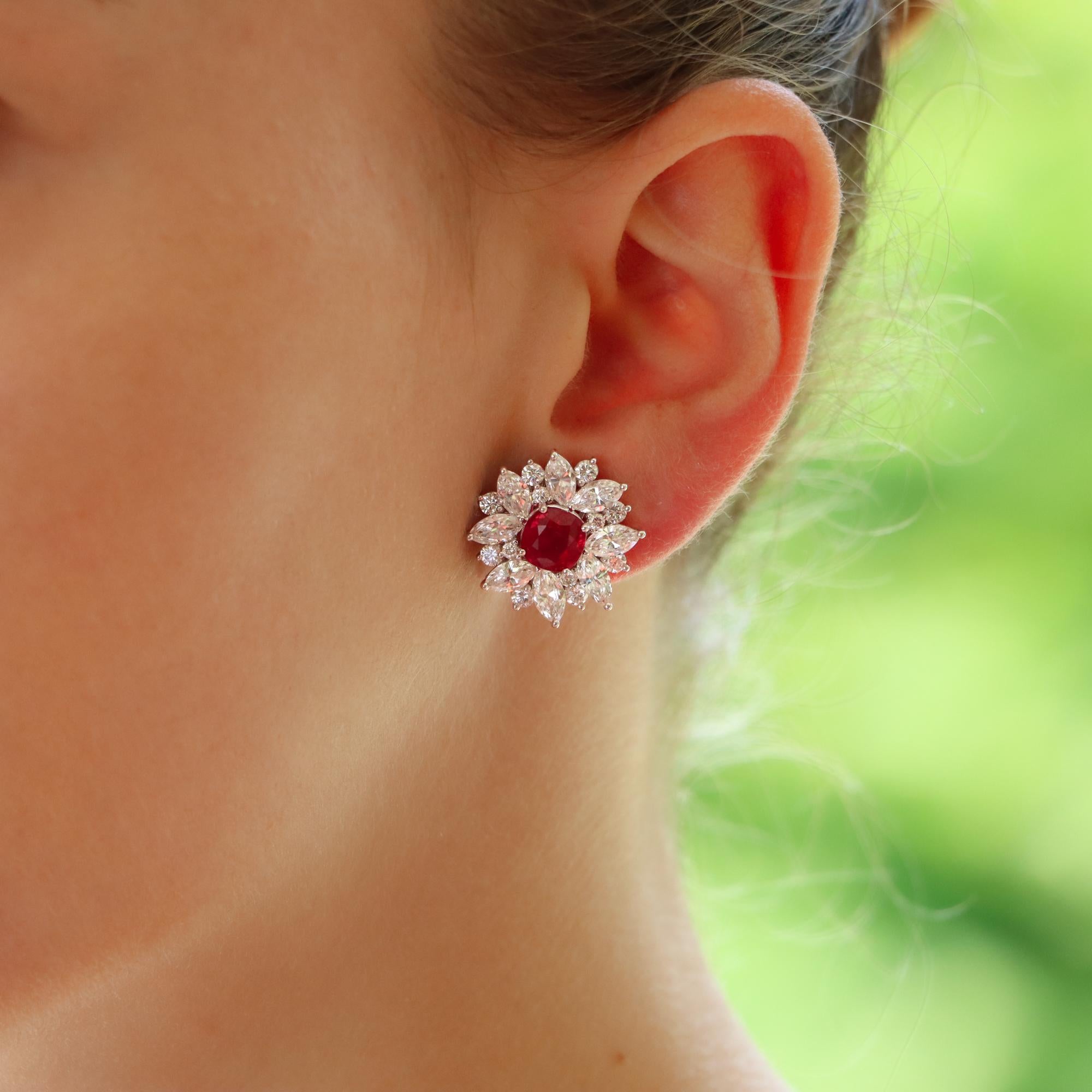 A spectacular pair of vibrant red ruby and diamond cluster earrings set in platinum.

Each earring features a central vibrant red cushion cut ruby. Surrounding each ruby are 8 marquise and 14 round brilliant cut diamonds. All of the stones are claw