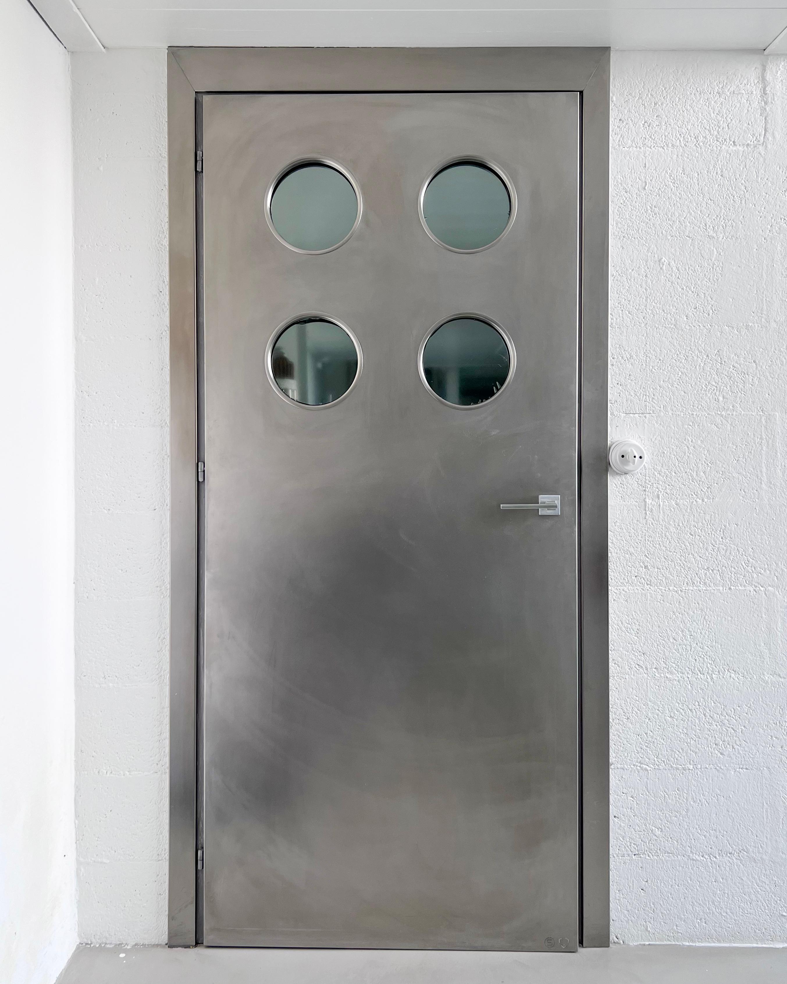 Zeitgenössische, maßgefertigte Metalltür aus Edelstahl mit runden Bullaugen, entworfen von Spinzi und hergestellt in Mailand.

Inspiriert von den Werken von Jean Prouvé, Portaluppi und den Designern/Künstlern dieser Epoche, wurde diese Tür um eine