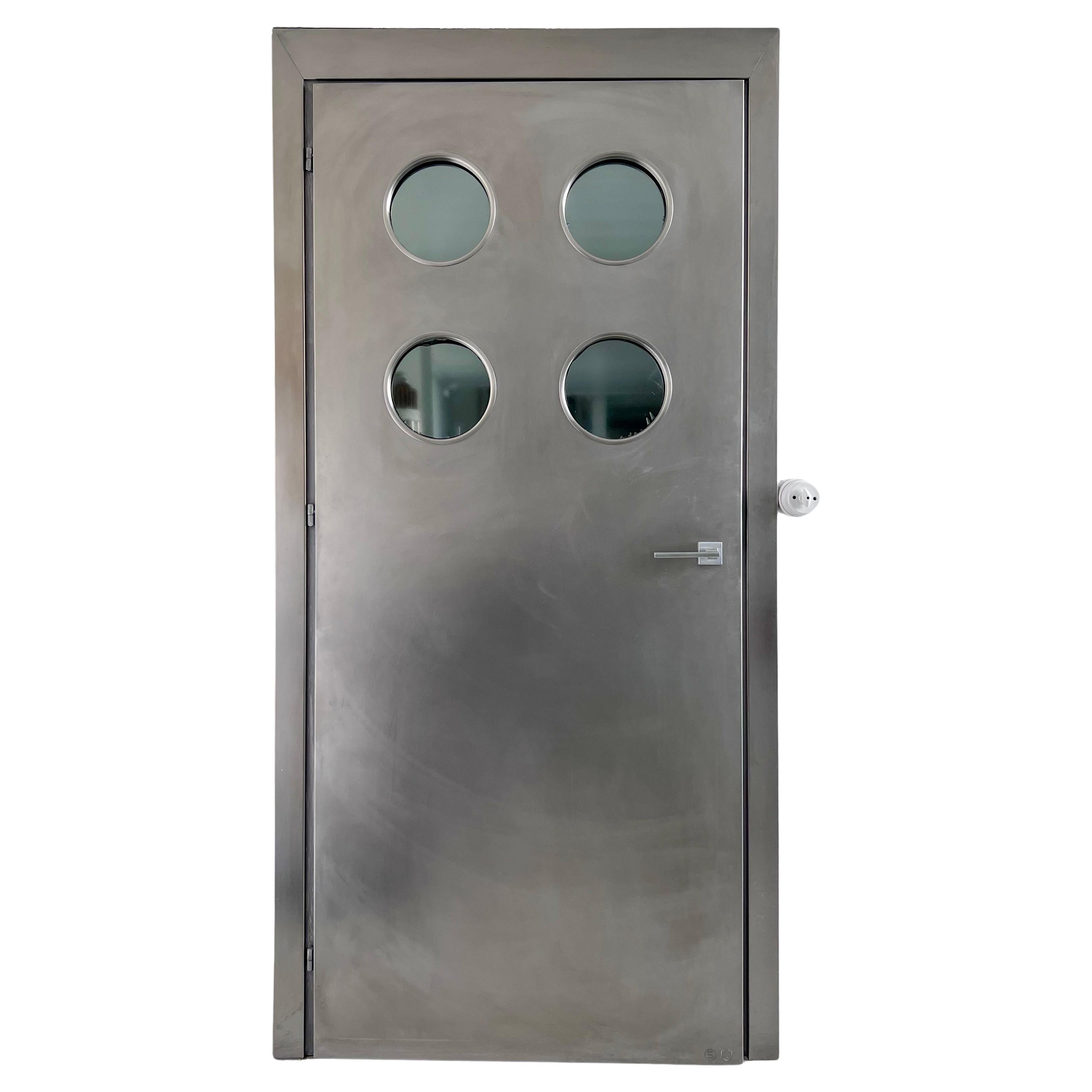 Contemporary custom made Spinzi stainless steel metal door with round portholes