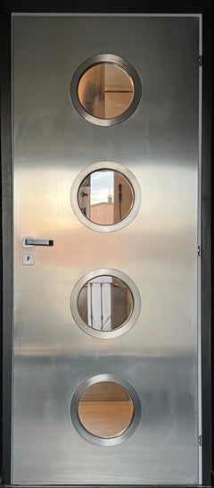 Porta contemporanea in metallo su misura in acciaio inox Spinzi con oblò rotondi