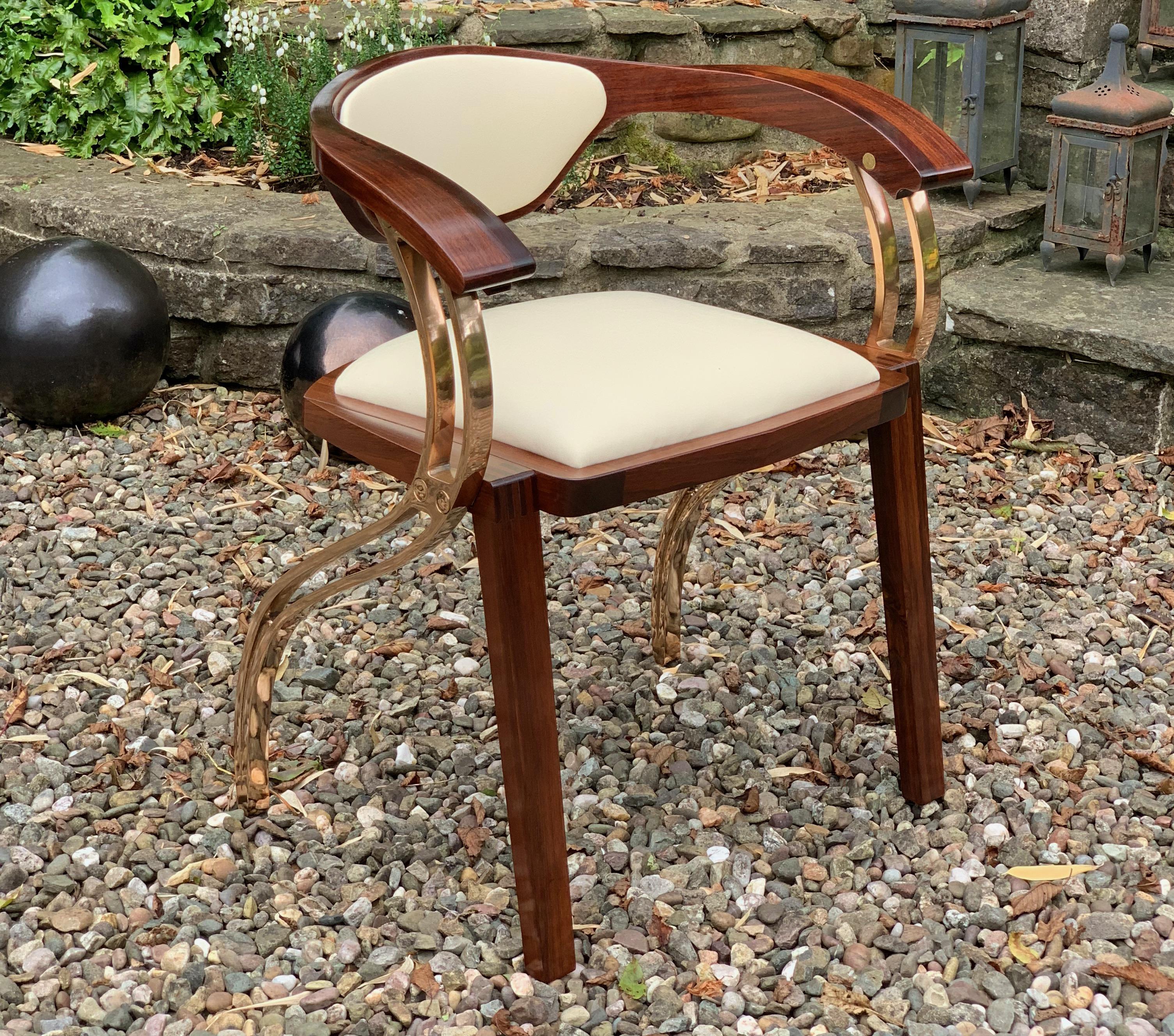 This made to order, limited edition, elegant and graceful, contemporary arm chair, constructed using an exotic figured walnut, cast bronze legs and an Italian white leather. It's creates a sculptural, fluid, contemporary design, that sits at ease in