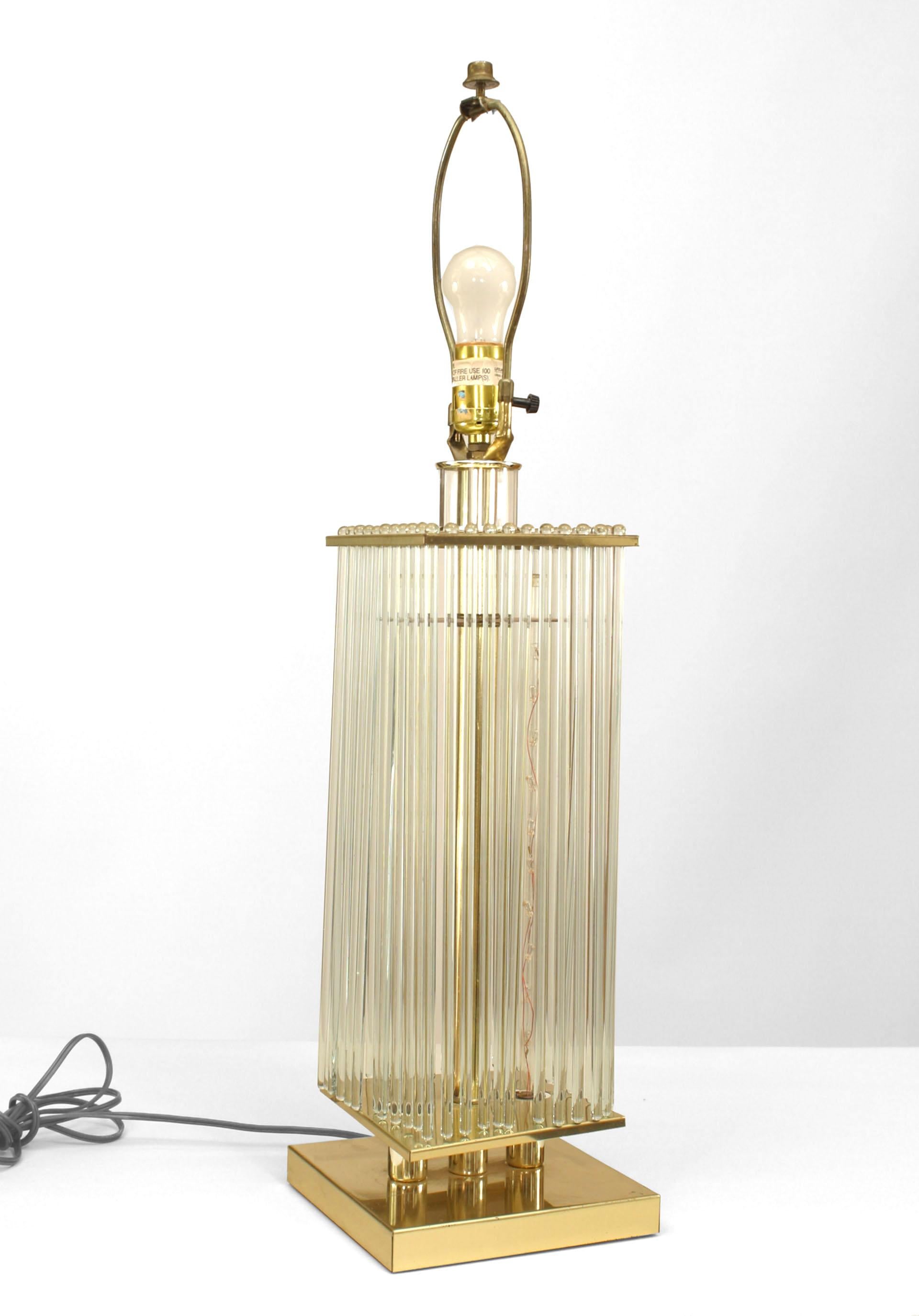 Lampe de table de design contemporain avec une base carrée en laiton sous des tiges en verre tubulaire transparent entourant un poteau central en laiton et deux tiges internes en verre avec des lumières.
   