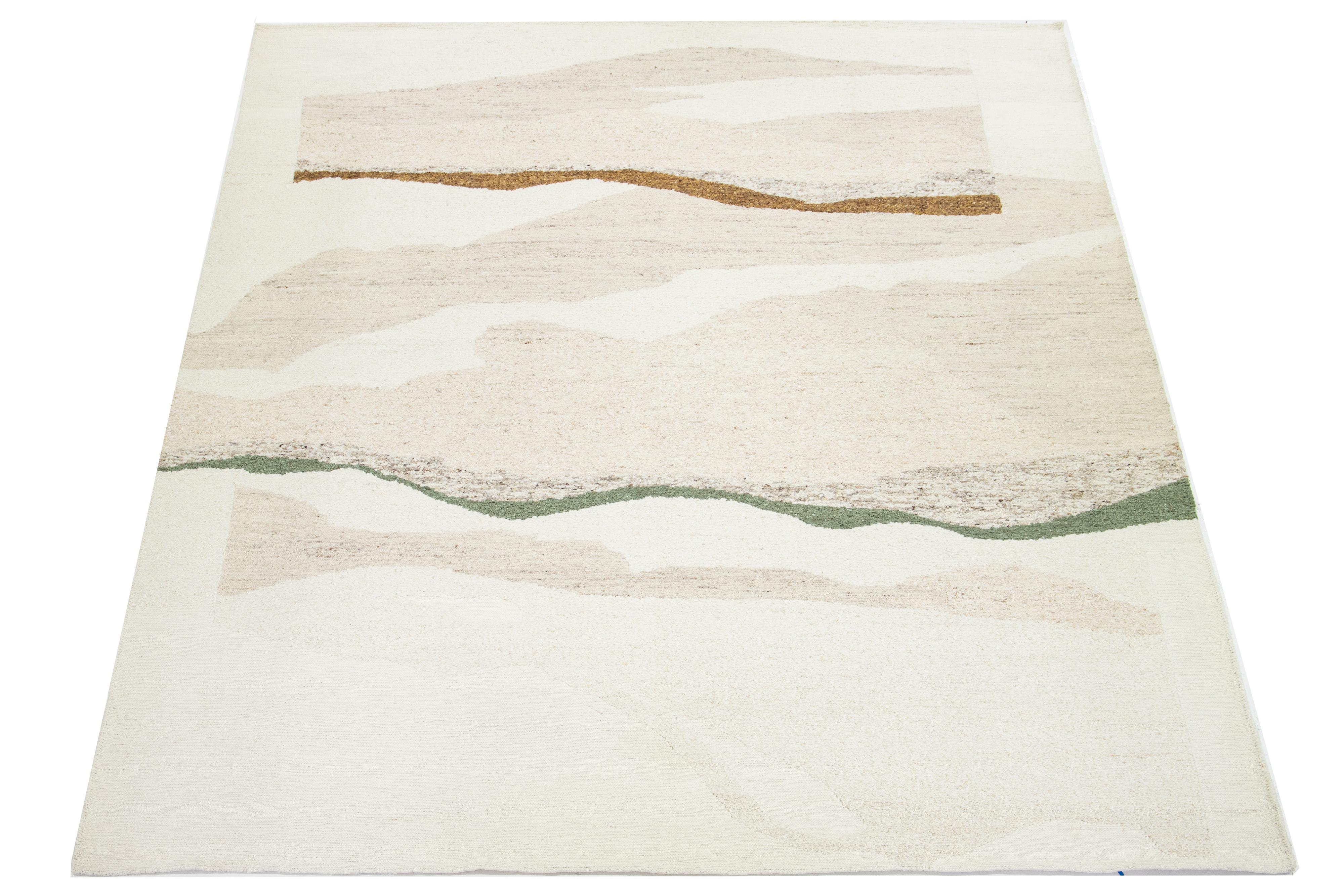 Questo bellissimo tappeto moderno in lana Soumak annodato a mano ha un campo color avorio. Presenta accenti verdi e marrone dorato in uno splendido disegno geometrico all-over.

Questo tappeto misura 11'10