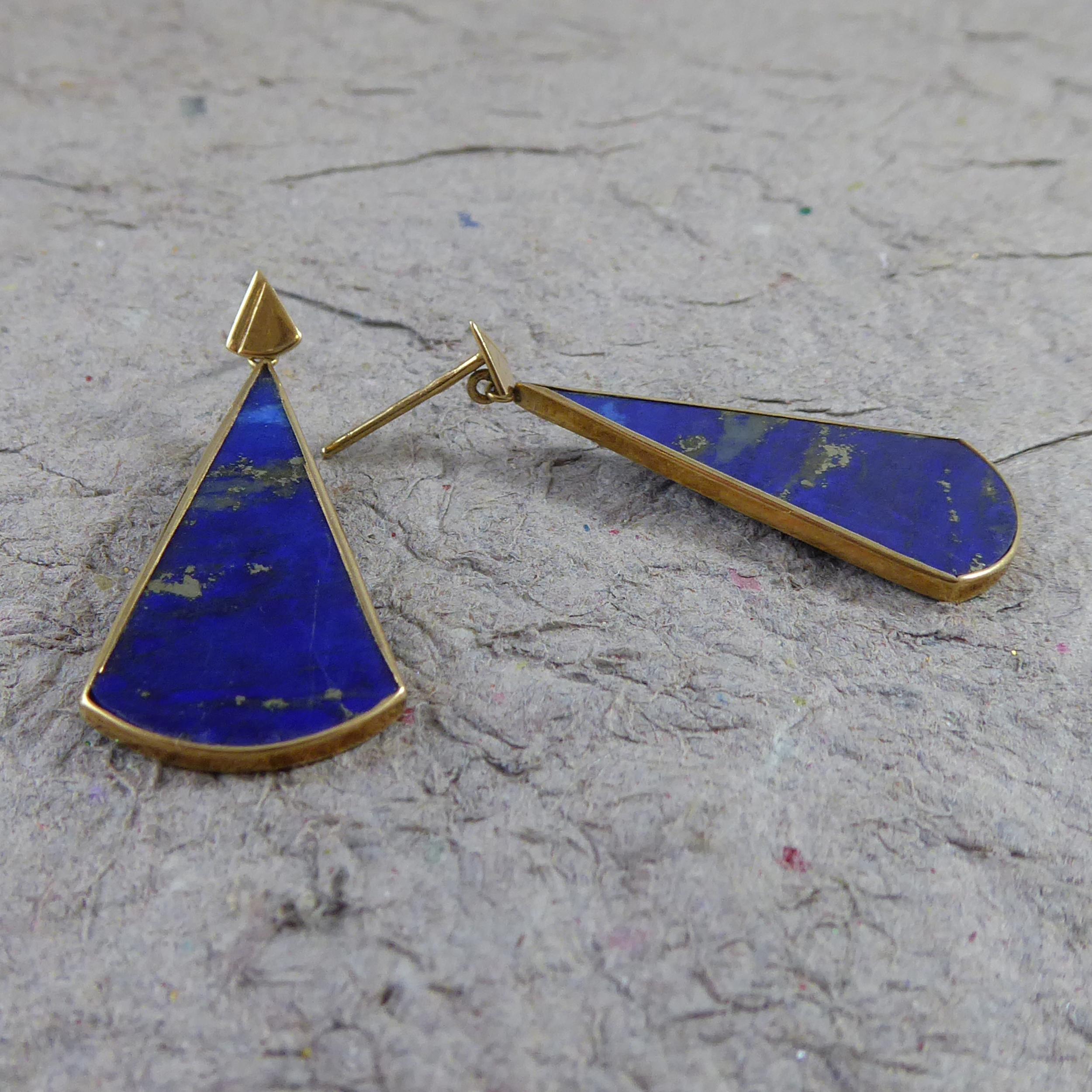 A pair of contemporary, pre-owned earrings, each earring is set with a wedge shaped lapis lazuli in a yellow gold mount  and suspending from a triangle shaped stud.  Testing as 9ct.  With post and butterfly fittings for pierced ears.  The drop