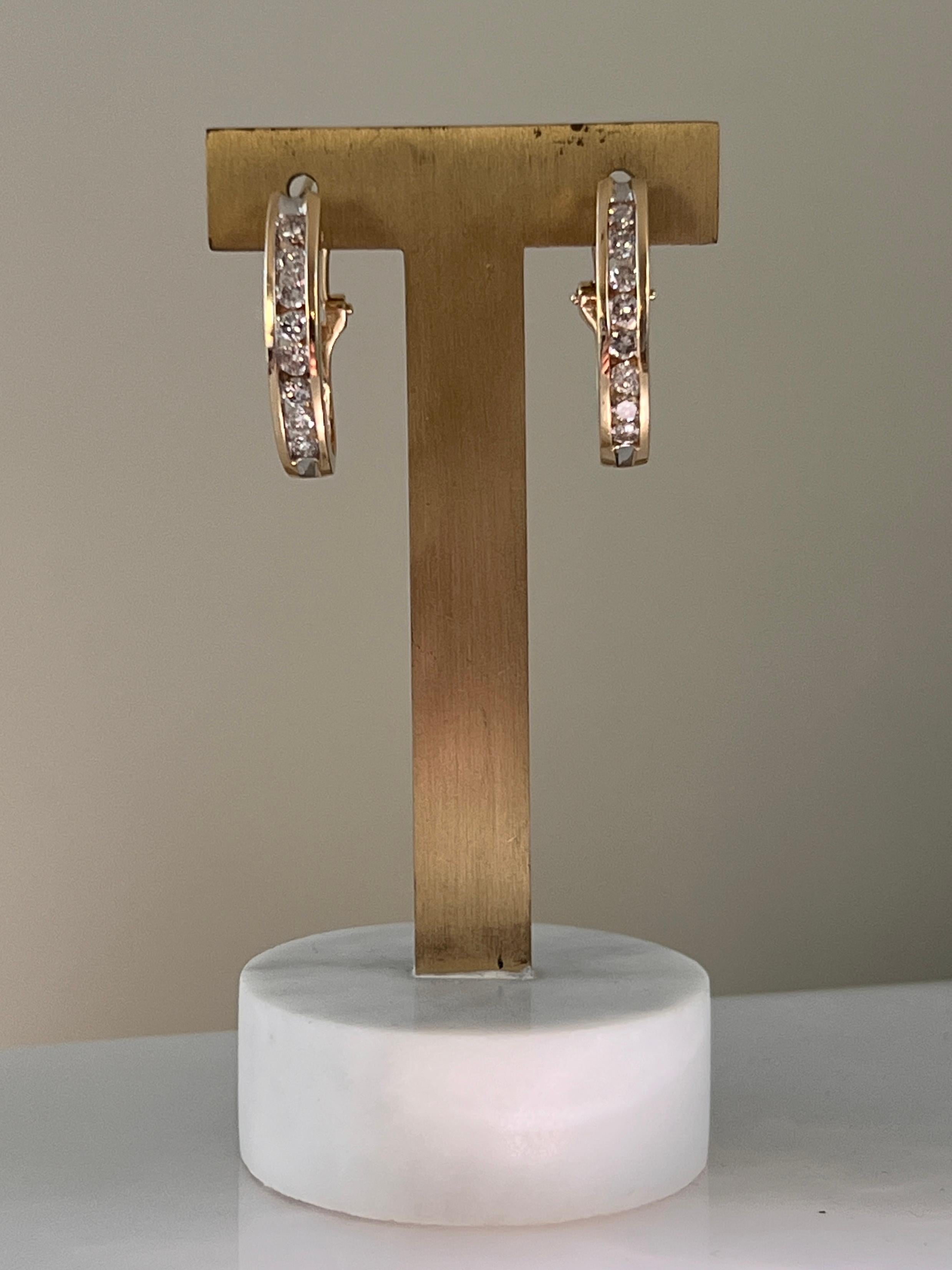 Estos impresionantes pendientes de aro ovalados de diamante en oro amarillo de 14 quilates combinan la elegancia contemporánea con un brillo sofisticado. Cada pendiente mide aproximadamente 1 x 3/4 pulgadas y tiene dieciséis diamantes brillantes