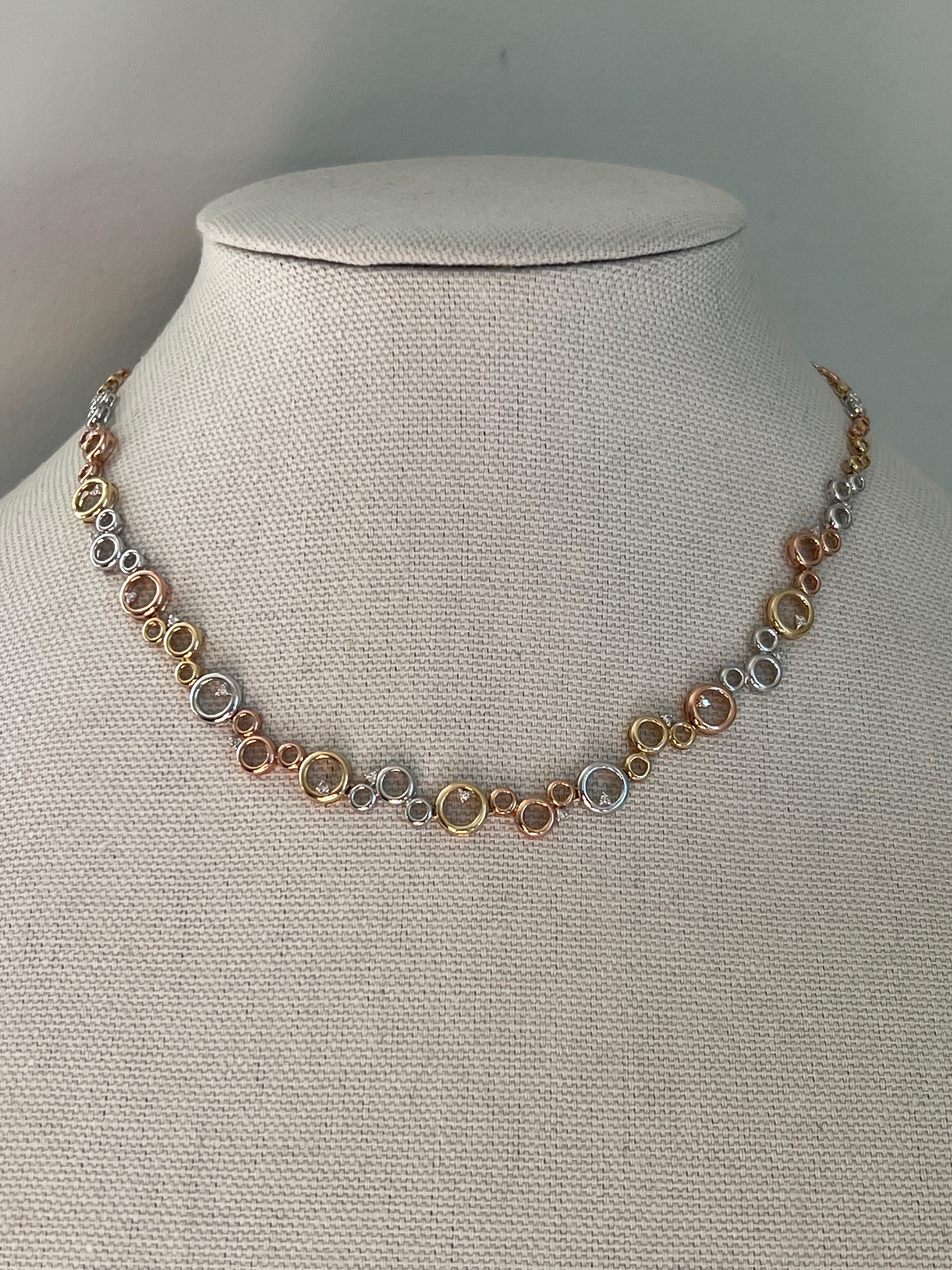 This 14-karat tritone gold necklace combines contemporary design with timeless appeal. Featuring a circular bubble motif, it is adorned with 19 round brilliant diamonds totaling 0.24 carats, with J color and I2 clarity. The circles gradually taper