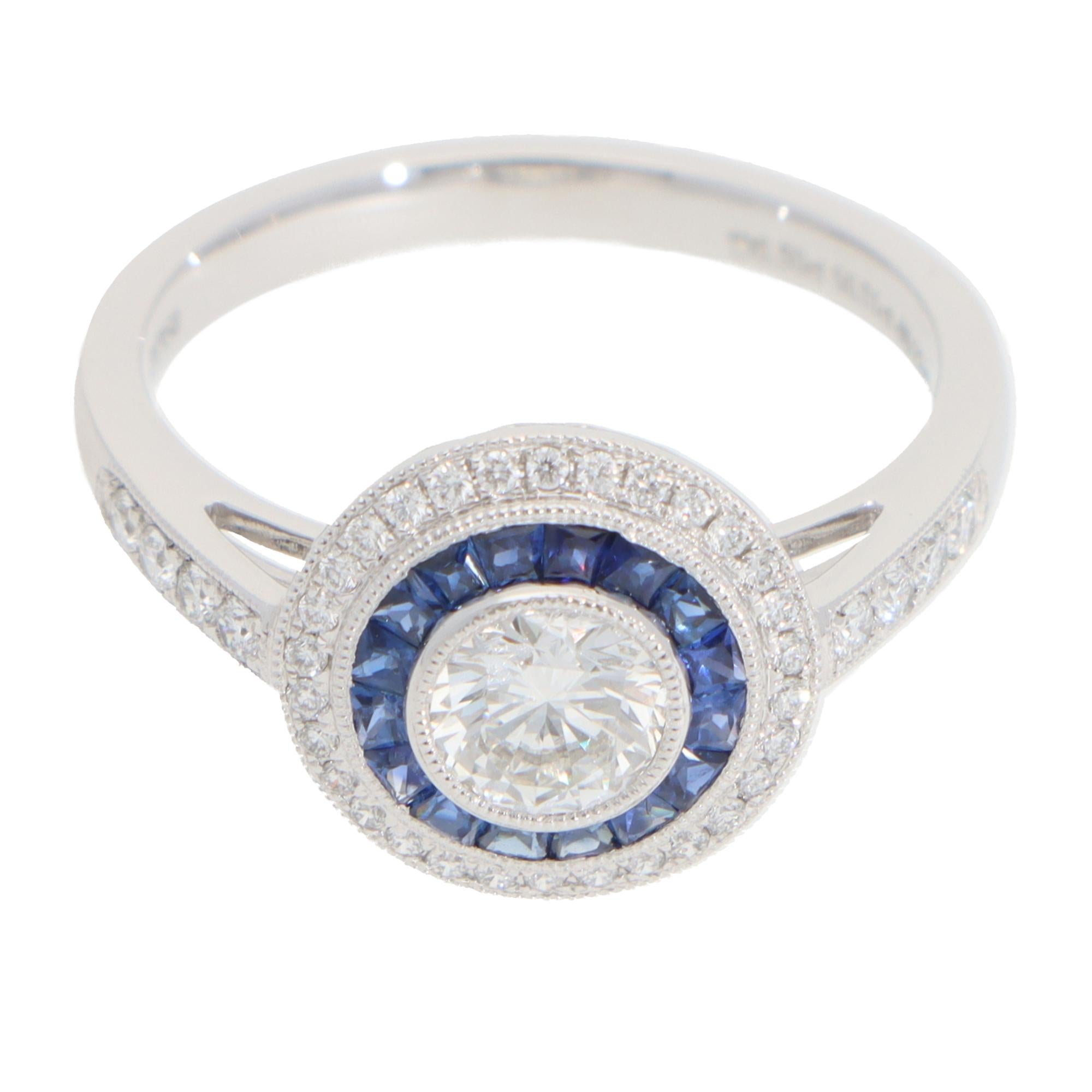 A beautiful Art Deco style diamond and sapphire double target ring set in platinum.

The ring is predominantly set with a sparkly round brilliant cut diamond in a bezel setting with bead detailing. Surrounding this beautiful diamond are two targets
