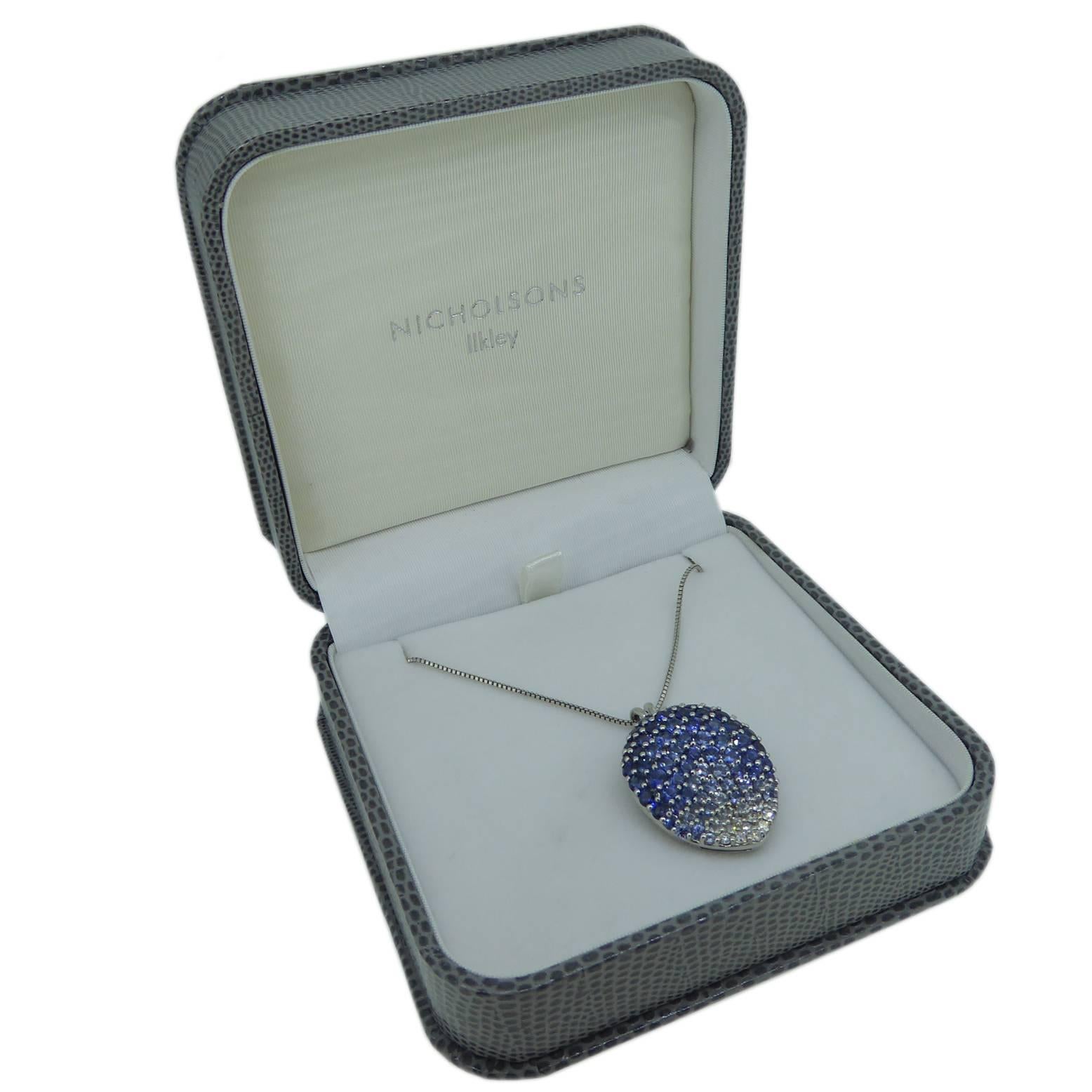 A very unusual pear shaped pendant pave set with brilliant cut diamonds are sapphires coloured blue and fading to white.  The pendant has a split chain runner in polished white metal and is complete with a platinyum box chain that fastens with a