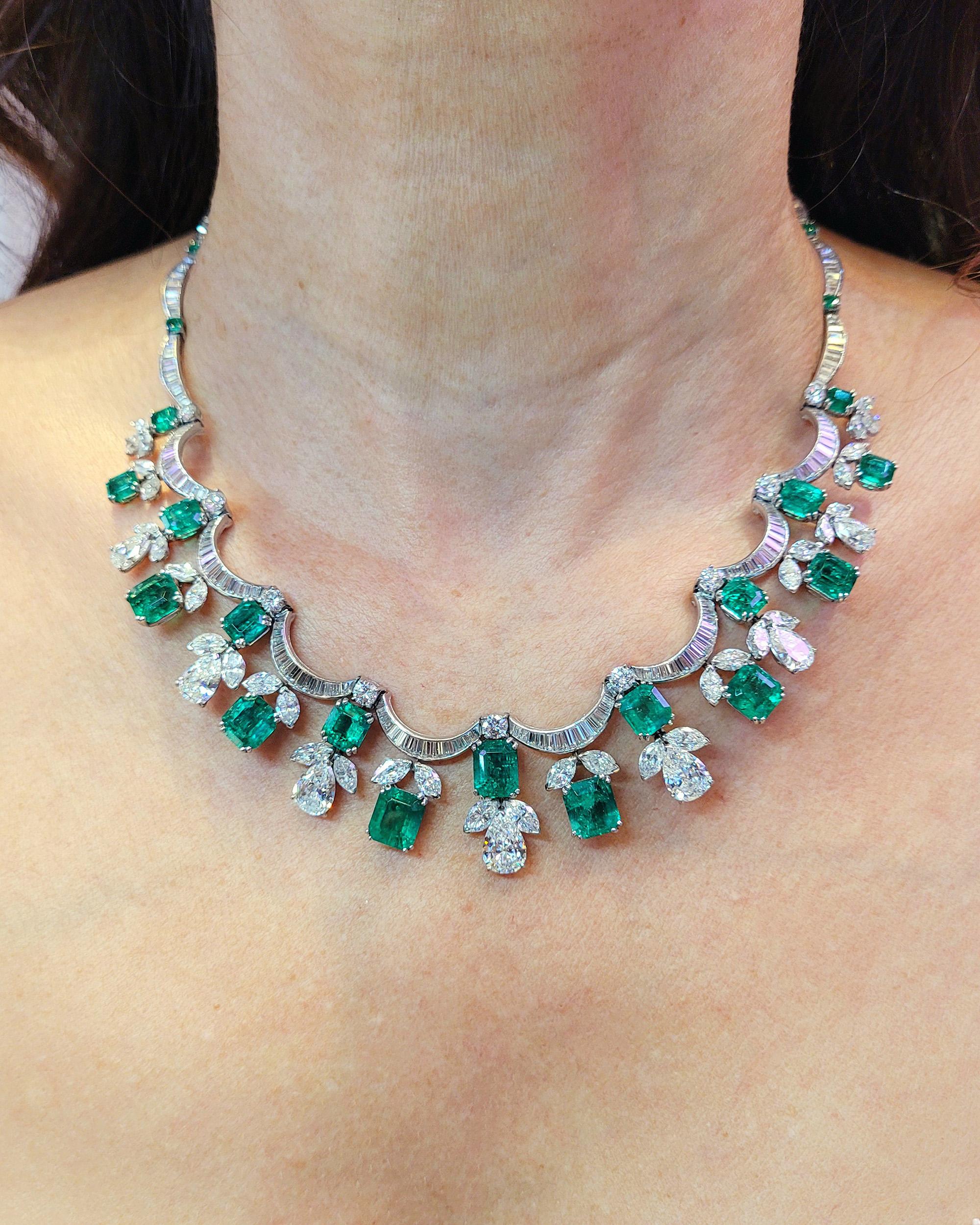 Twenty shimmering scalloped ribbons of baguette diamonds—twelve shallows and eight deeply curved—undulate around the neck interspersed with circular-cut emeralds and circular-cut diamonds and in this exquisitely designed Contemporary Diamond Emerald
