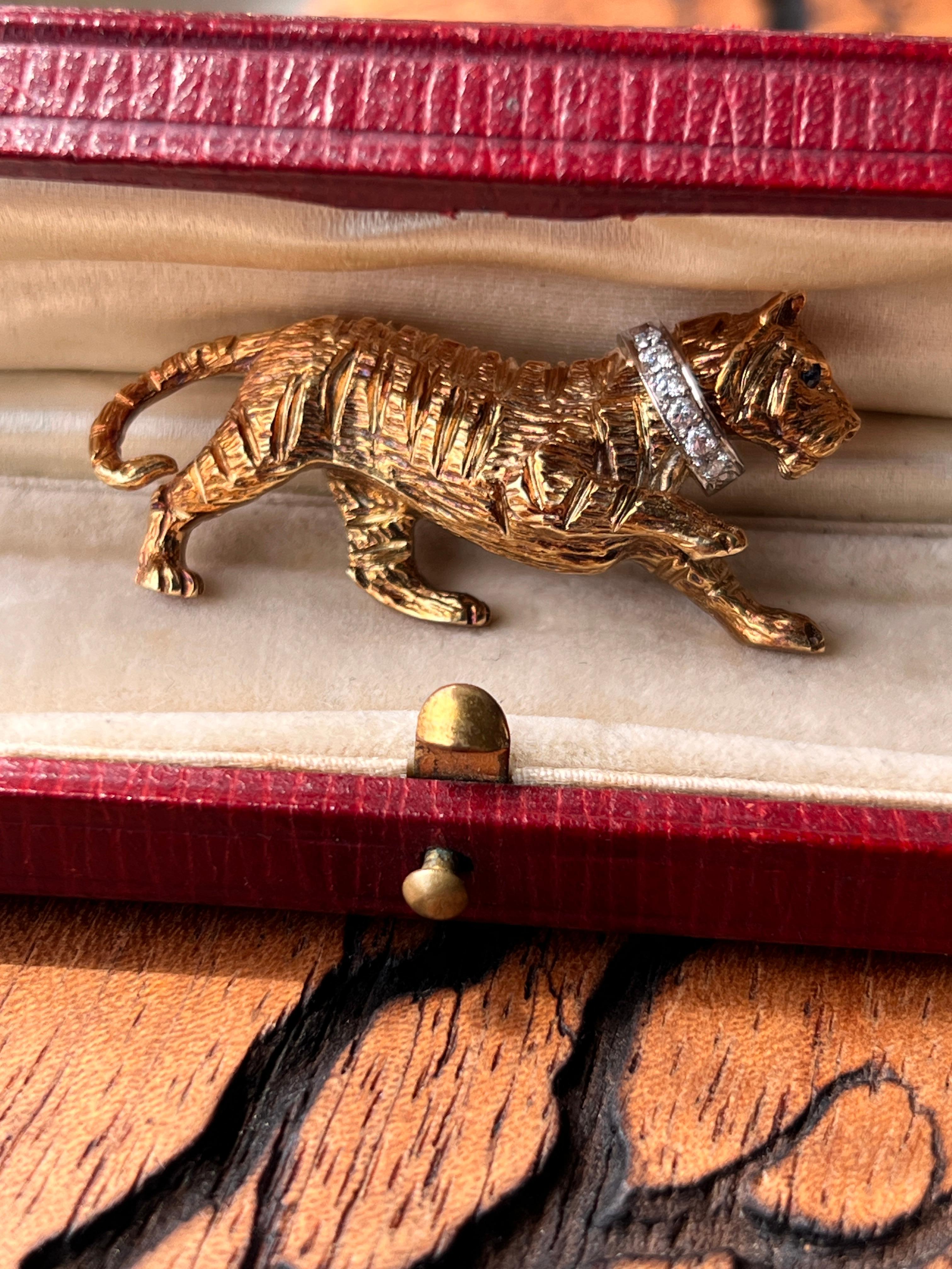 Questa spilla contemporanea a forma di tigre in oro giallo e bianco 14K ha un design audace ed elegante. L'occhio di tigre è incastonato con uno zaffiro blu rotondo di 1,3 mm per un peso di circa 0,01 carati, mentre sei diamanti rotondi e brillanti