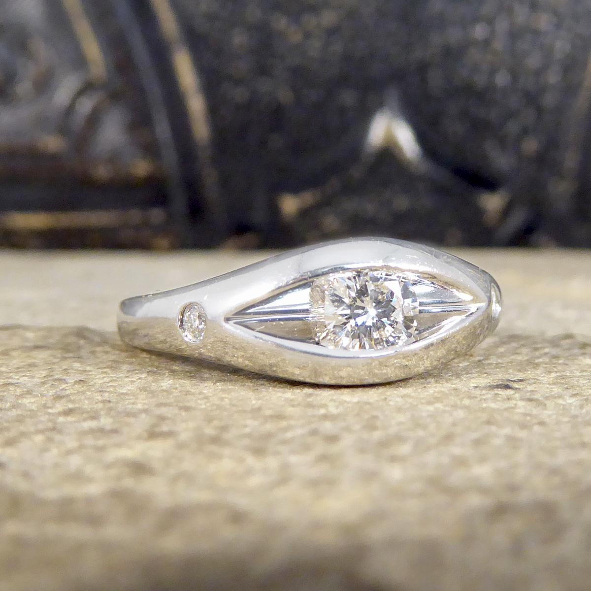 This beautifully sparkly and unusual ring holds a Brilliant cut Diamond weighing 0.30ct. The Diamond is set into the band in a rub over setting with the rub over points at the top and bottom having a space either side of the Diamonds giving the ring