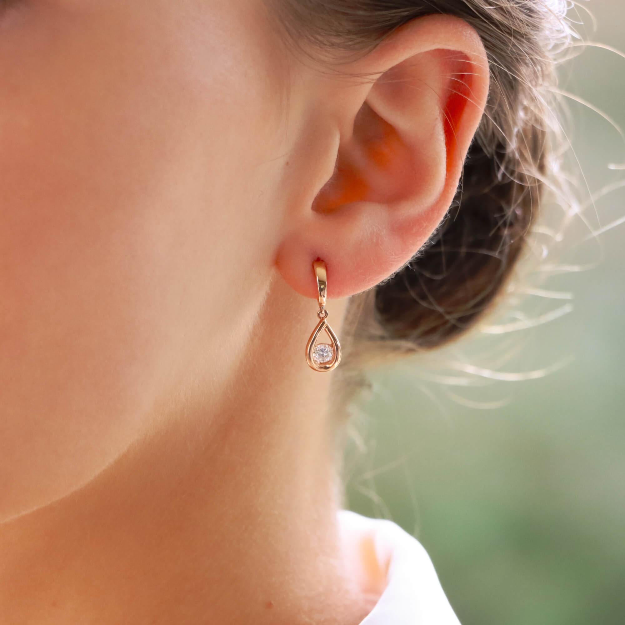 A beautiful pair of contemporary diamond drop earrings set in 14k rose gold.

Each earring is predominately set with a round brilliant cut diamond which is bezel set in a tear drop shaped motif. This tear drop hangs freely from a petite rose gold