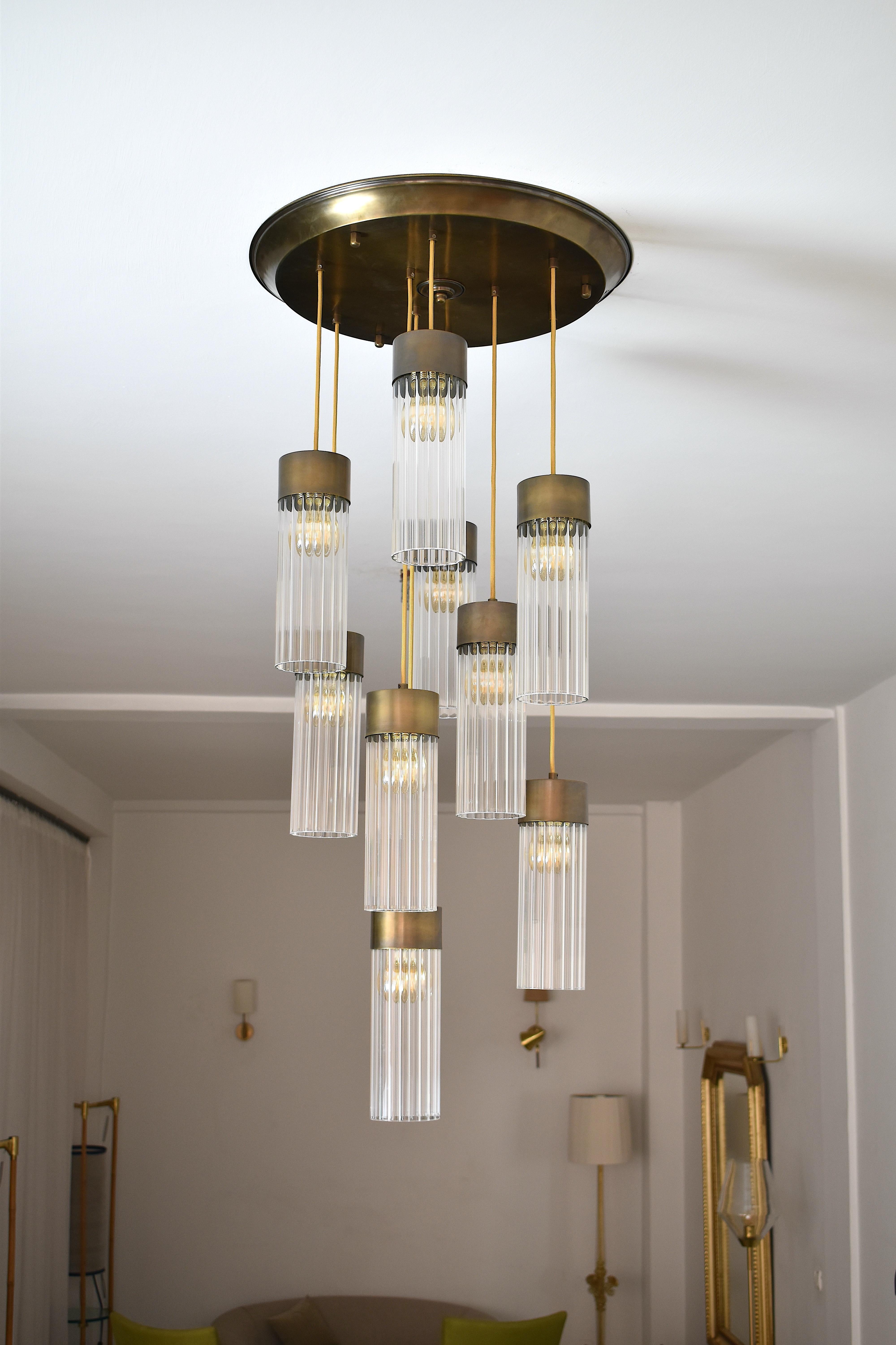 Handcrafted 9 multi-pendant light, with shades adjusted to different heights. Designed with rigged handblown glass shades, solid brass fixation plates, and brass shade caps. 
By Jonathan Amar Studio.
 